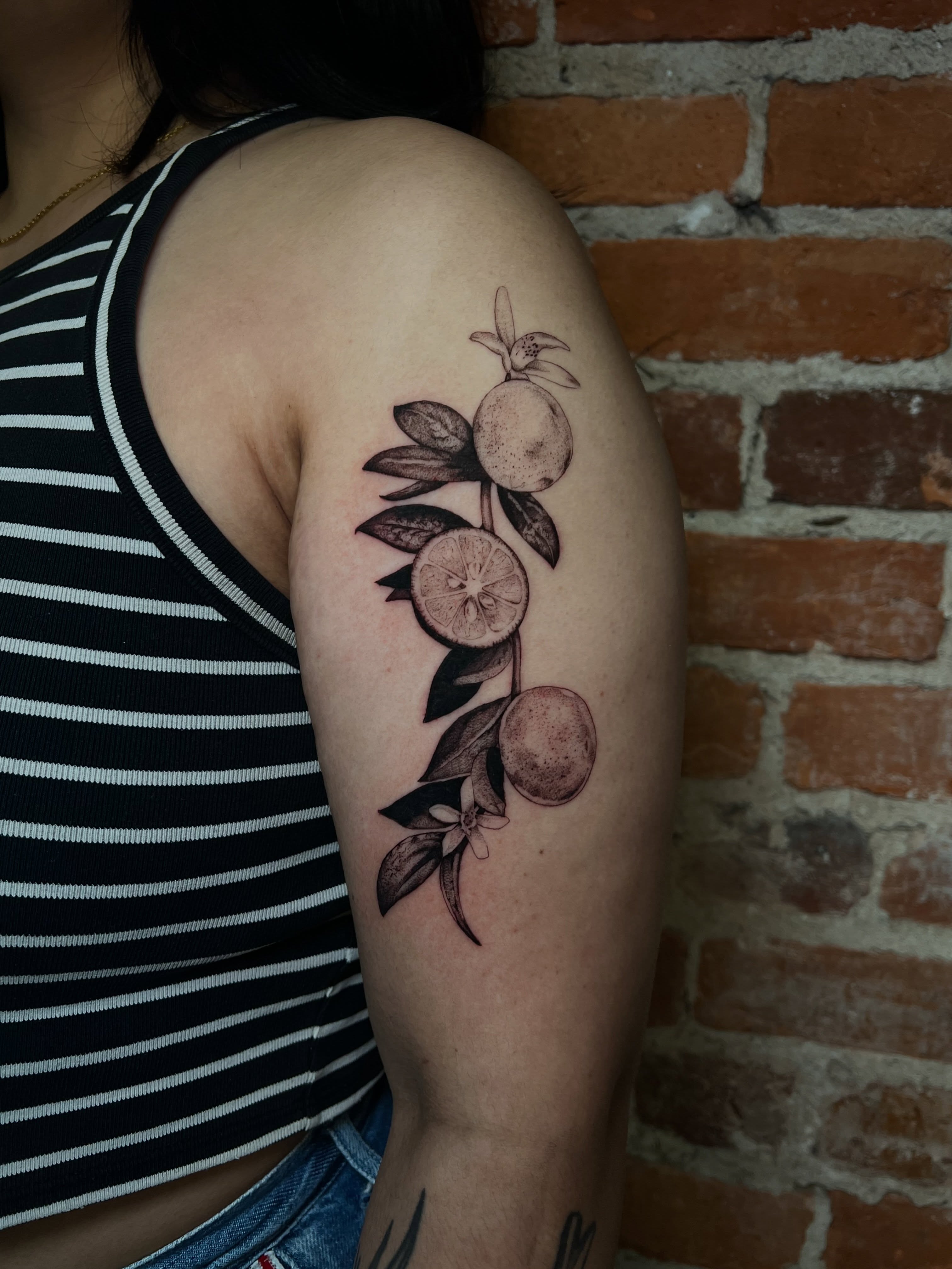 Fruit branch black and grey tattoo on the upper arm by Uncomfy Comfort Tattoos LLC