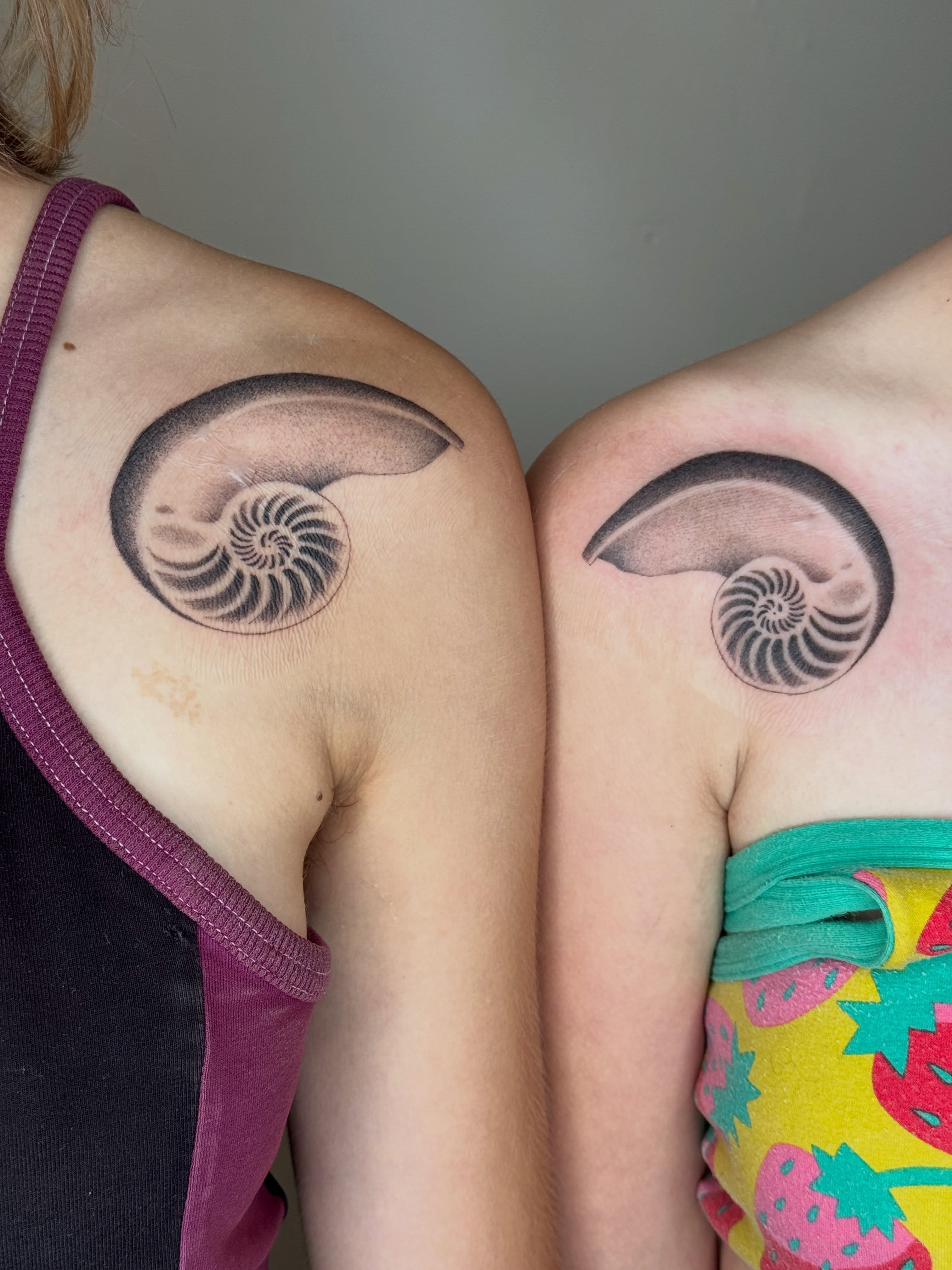 Nautilus shell black and grey tattoo on the shoulder by Monica Reynolds