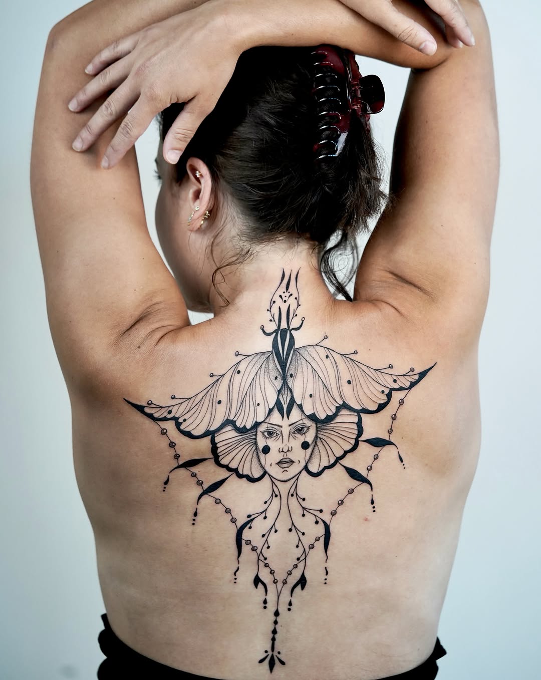 Woman's face with butterfly wings geometric tattoo on the back by Nika