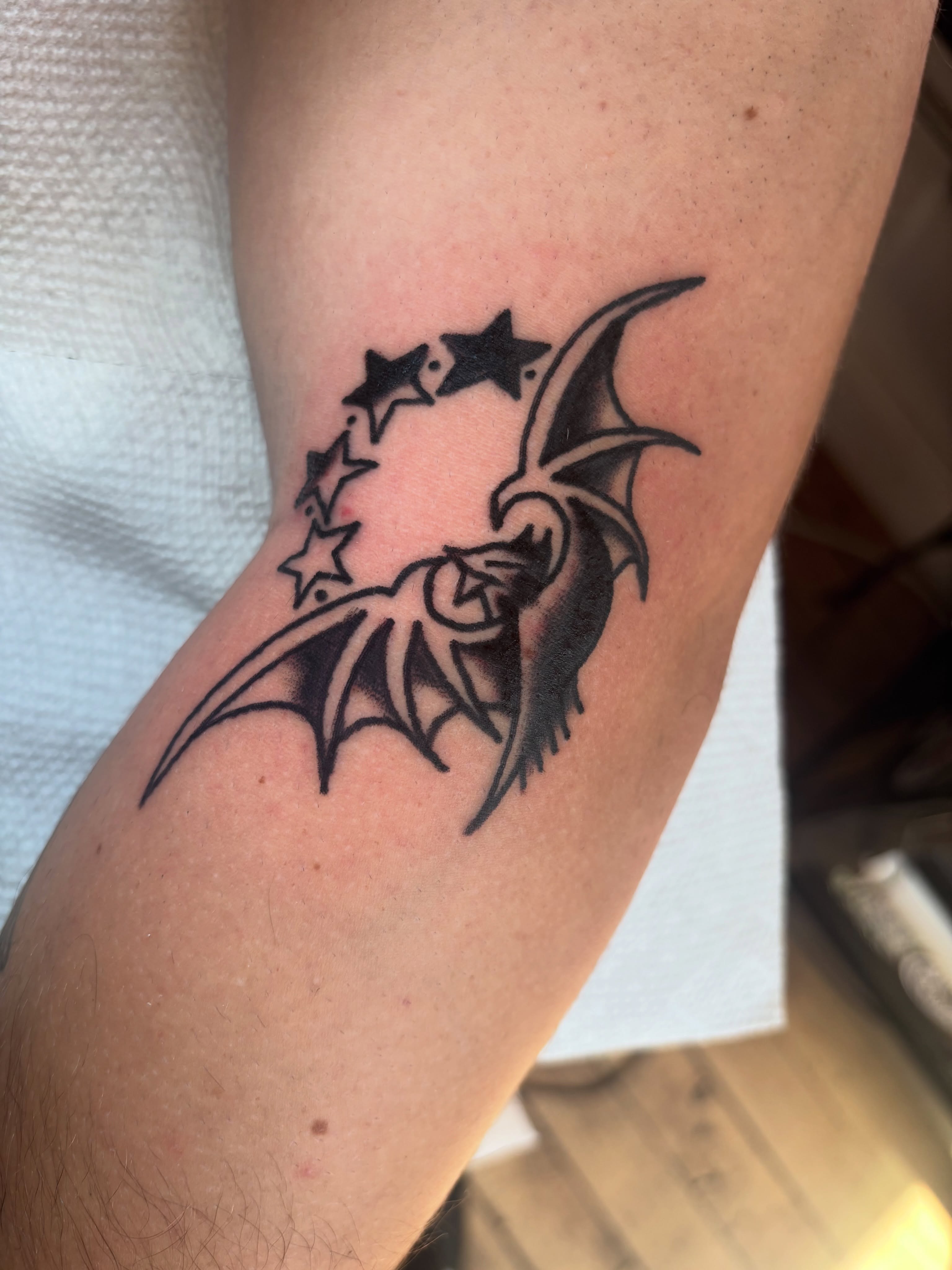 Bat and stars black and grey tattoo on the forearm by Nick