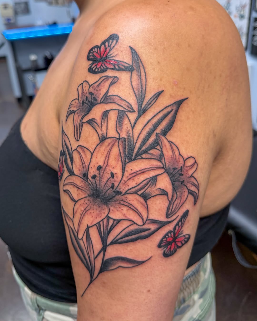 Lilies and butterflies realism tattoo on the shoulder by Zac Tattooer