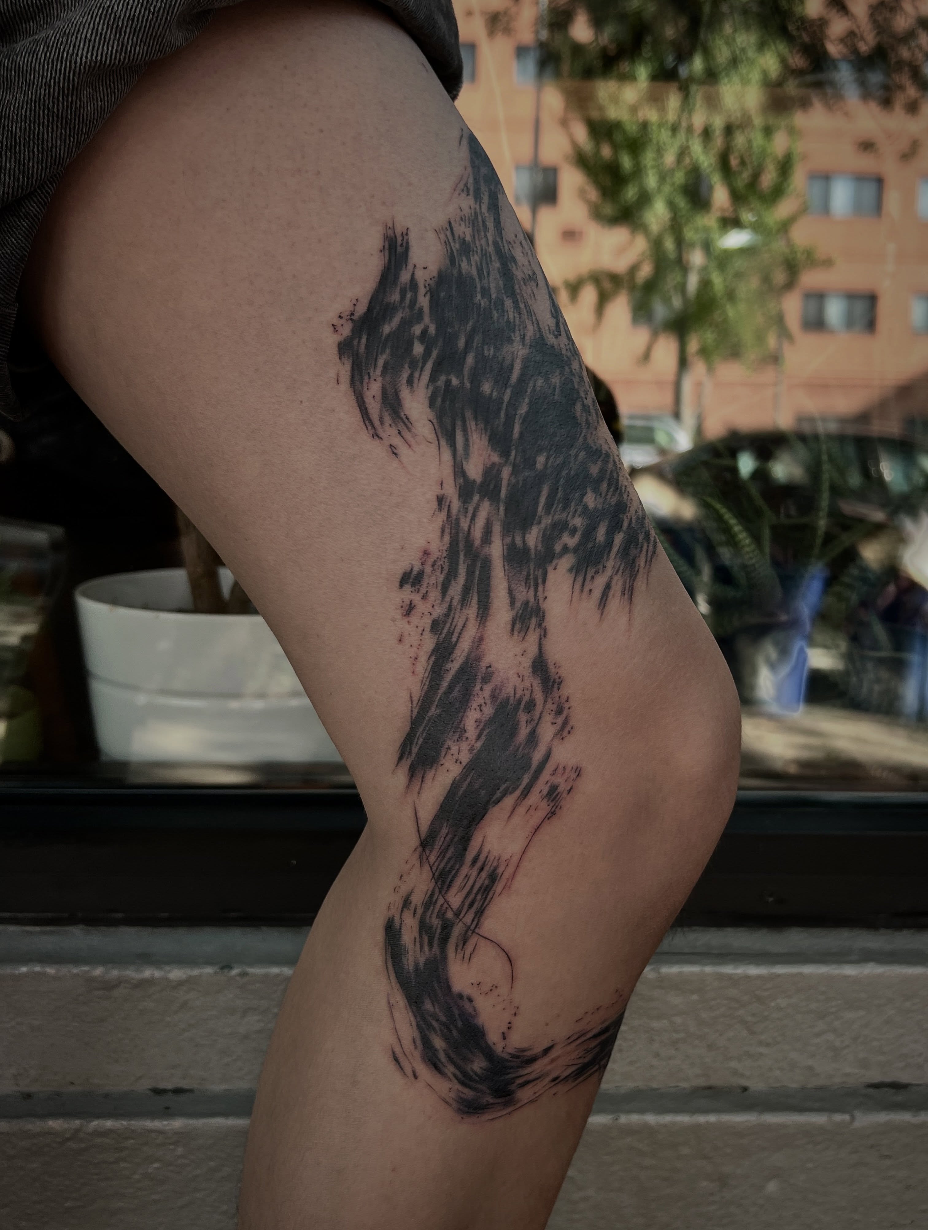 Abstract brushstroke black and grey tattoo on the thigh by Jen Rahman