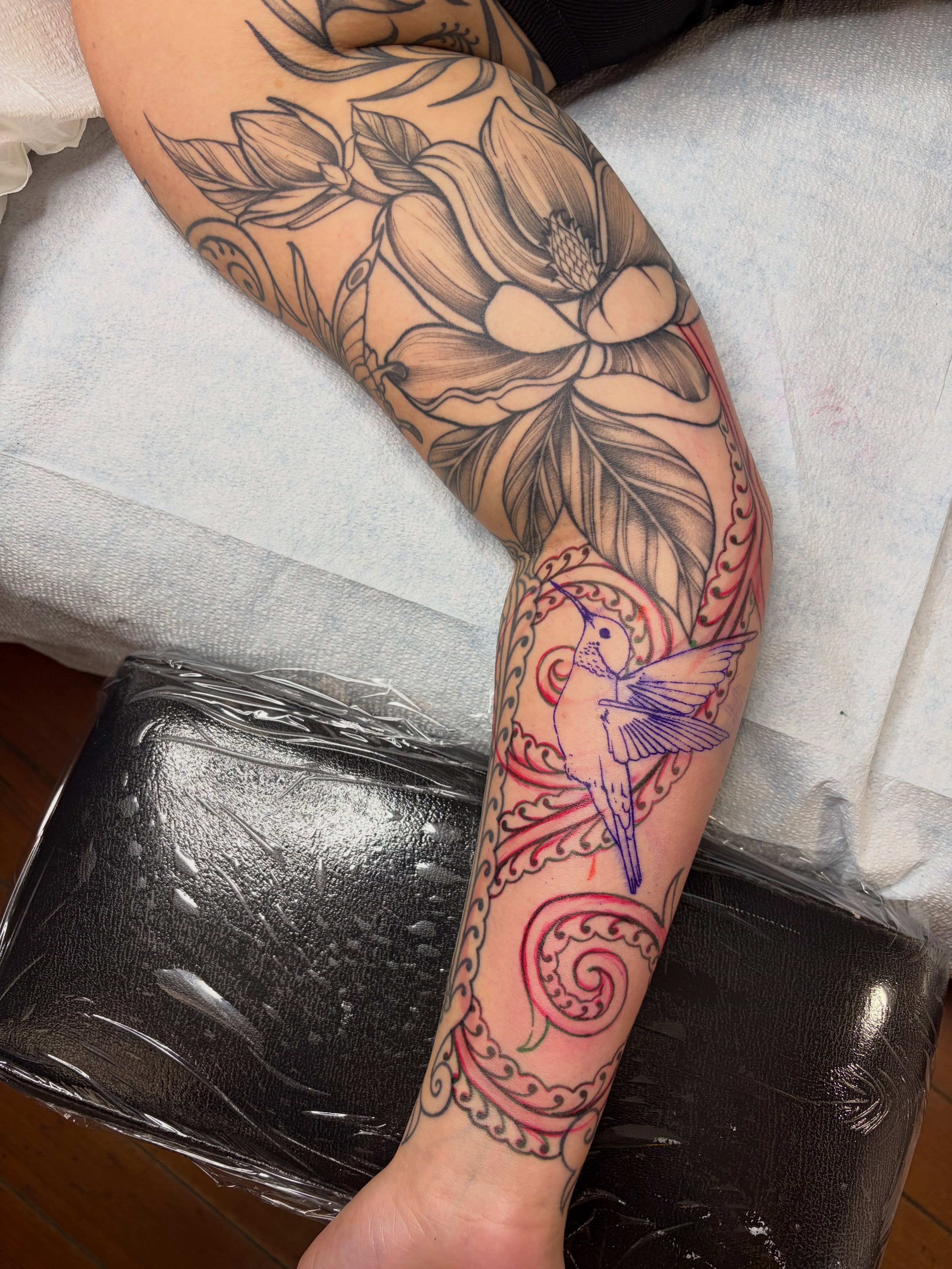 Hummingbird and floral black and grey tattoo on the forearm by Danika Brooke 🧿
