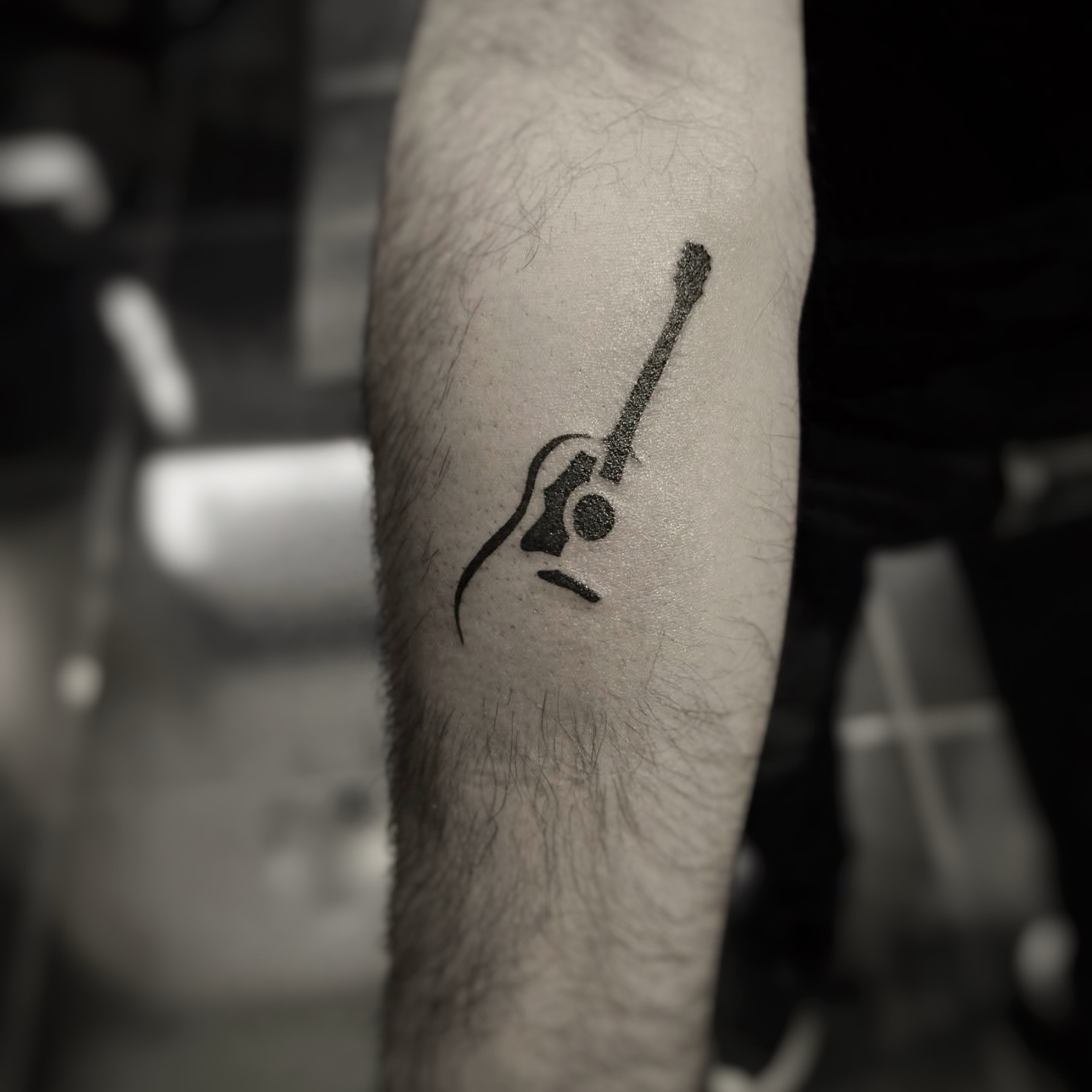Acoustic guitar minimalist tattoo on the forearm by Yana Aizen