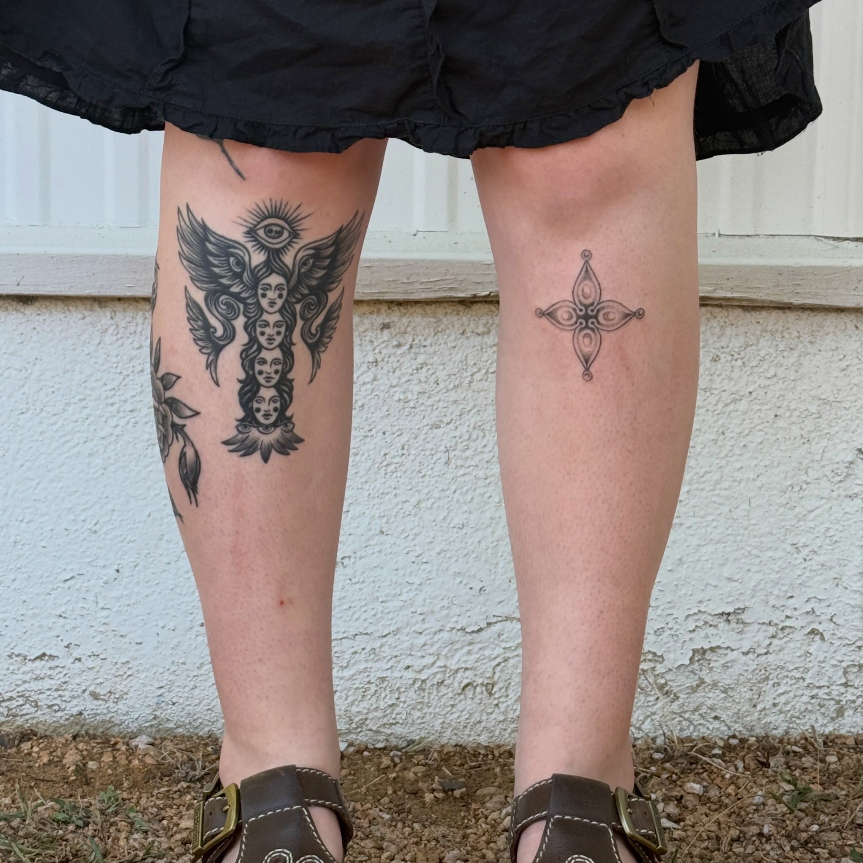 Wings and faces black and grey tattoo on the leg by springgreens