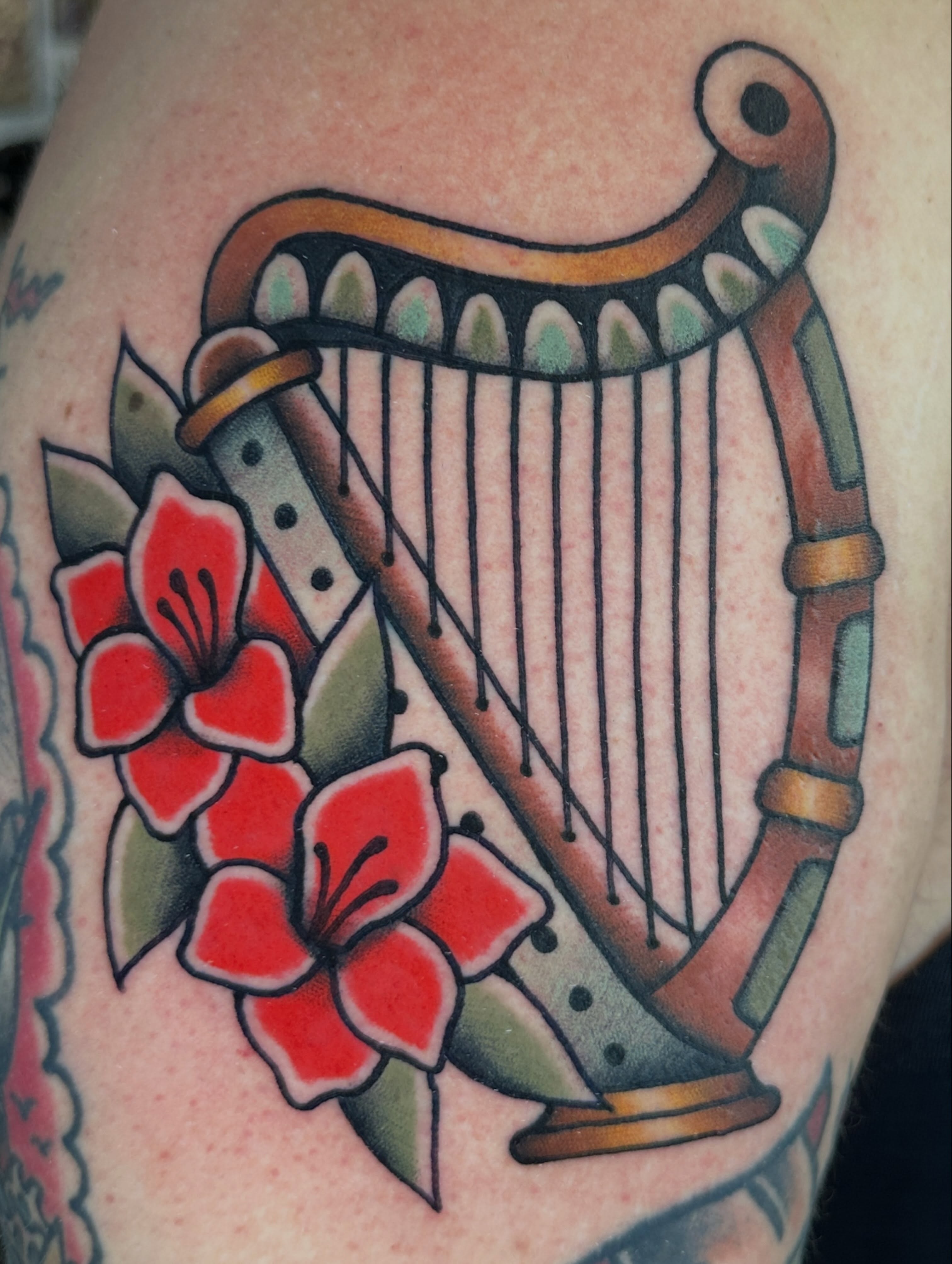 Harp and flowers American traditional tattoo on the shoulder by Kyle Logan Frary