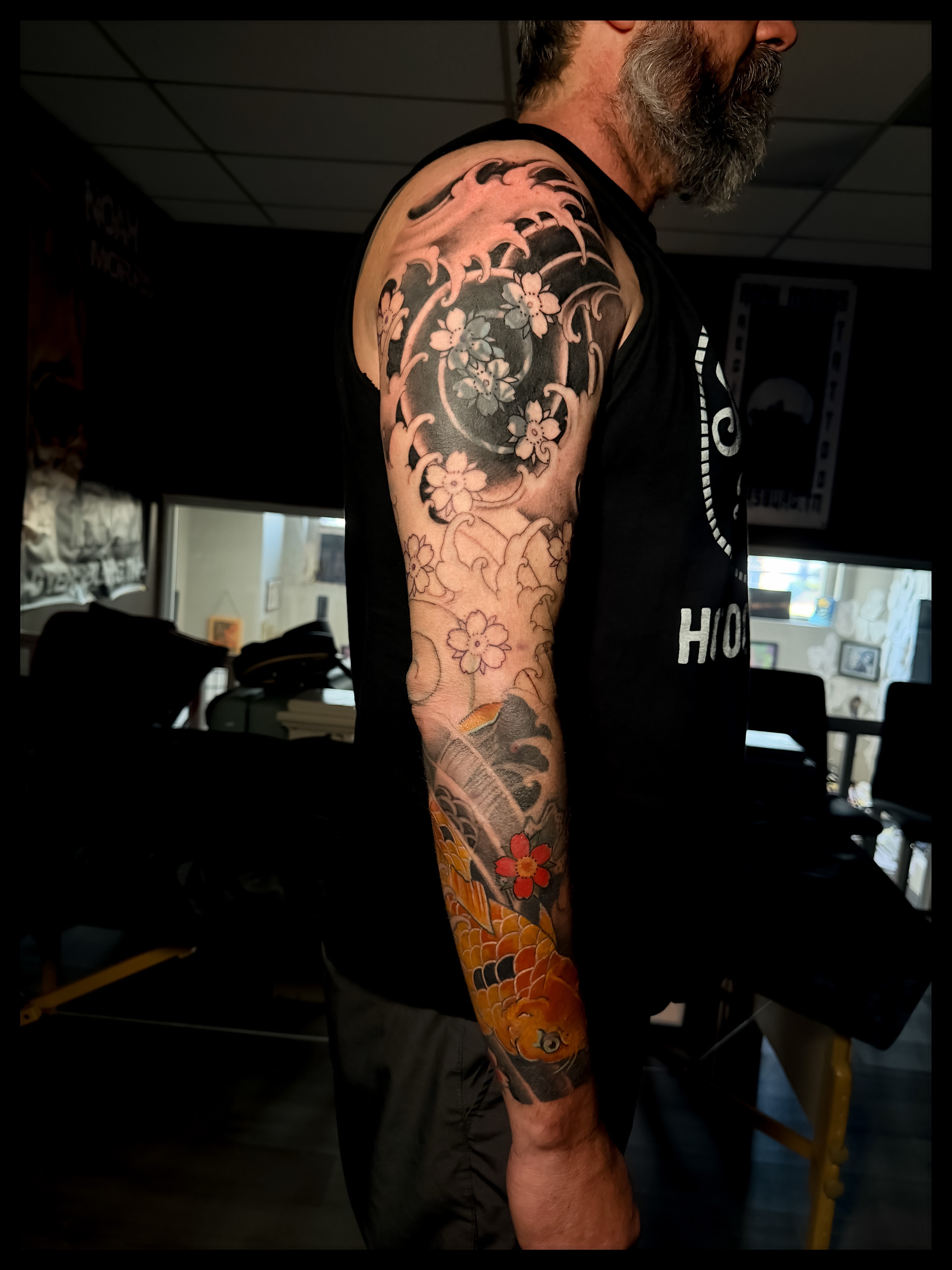 Koi fish and floral japanese irezumi tattoo on the upper arm by Noah Morris