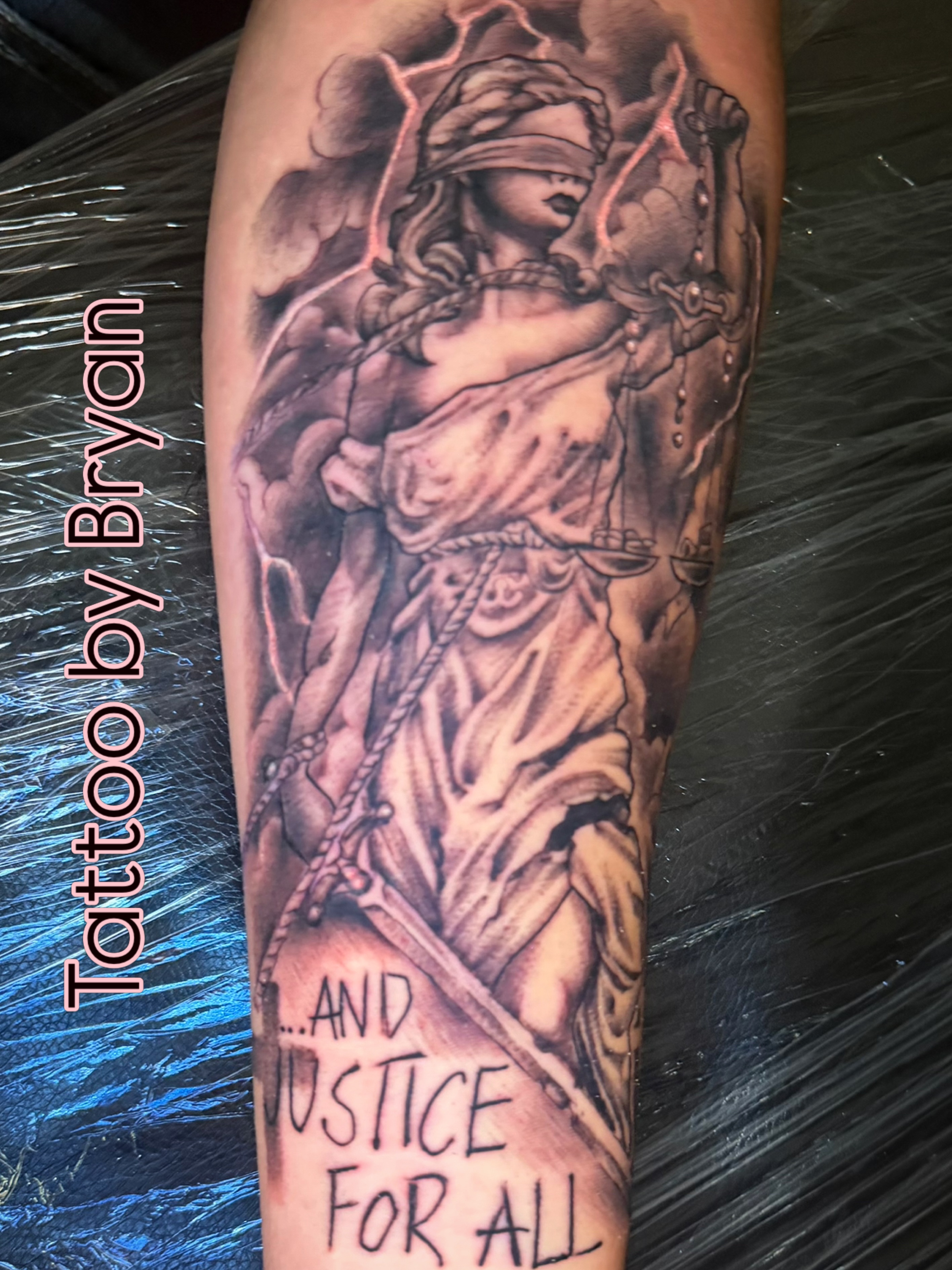 Justice black and grey tattoo on the forearm by Bryan Hunt