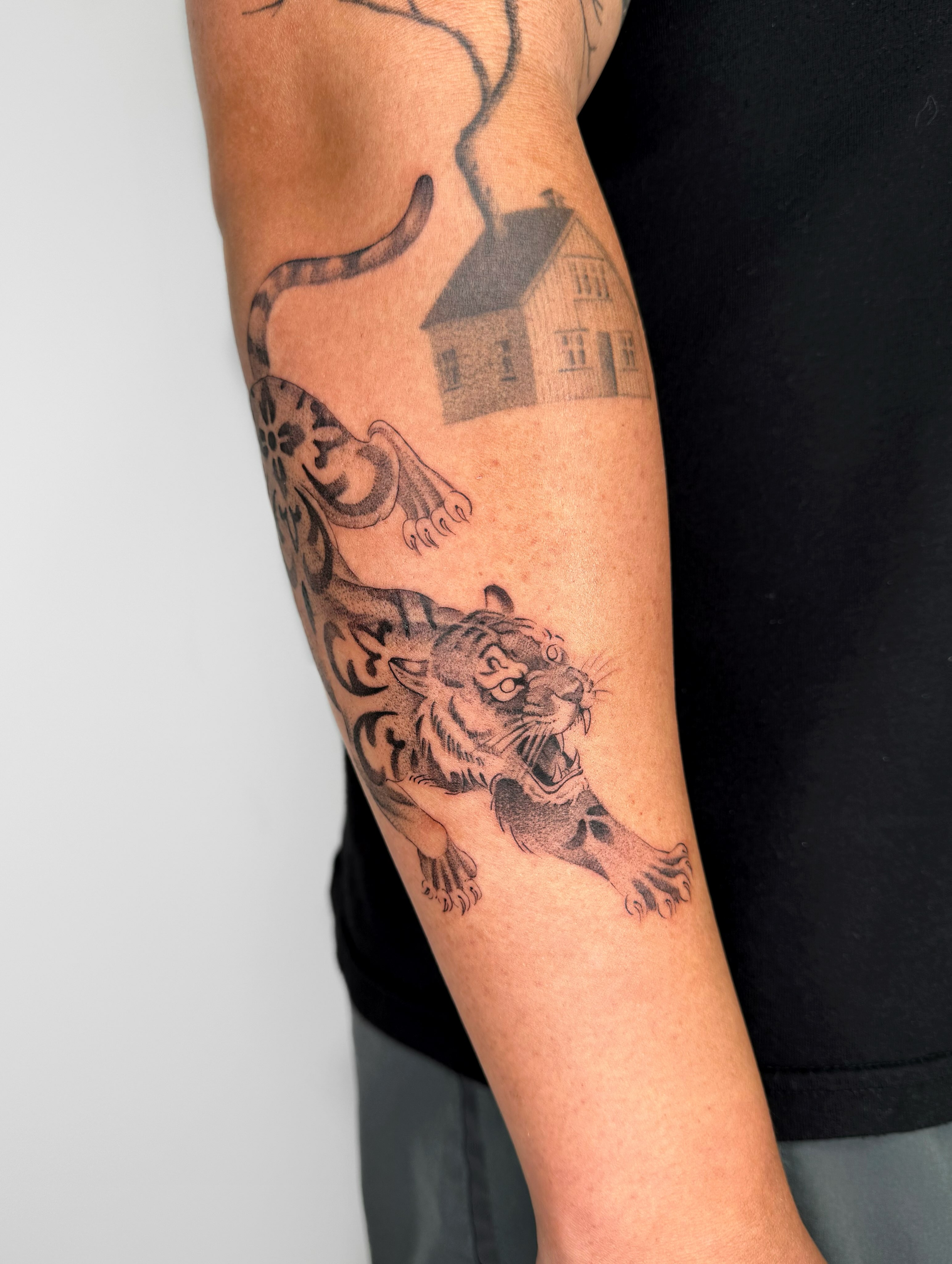 Tiger and house black and grey tattoo on the forearm by Alyssa . Villela