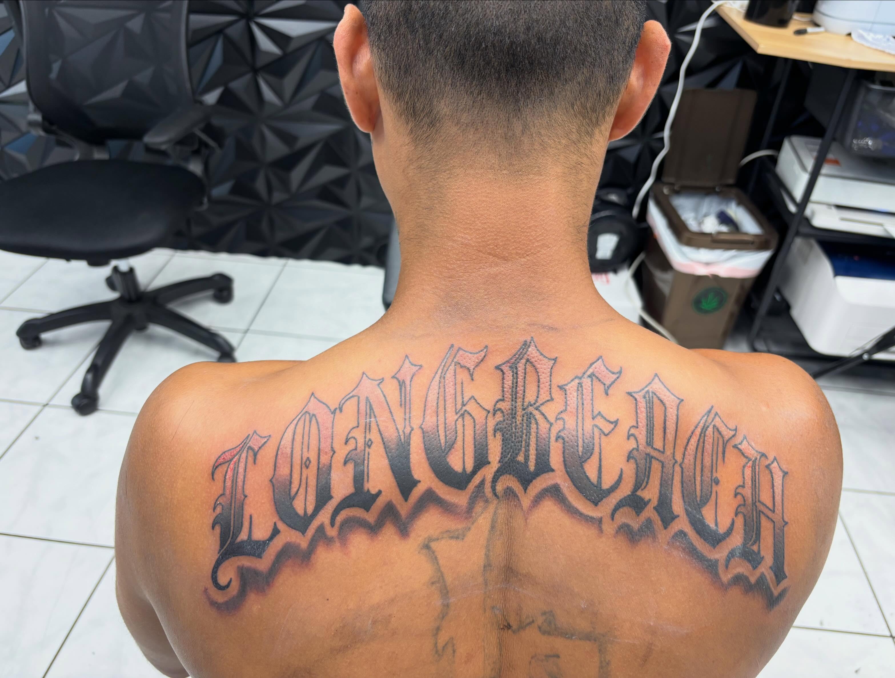 Longreach lettering script tattoo on the back by Shadows Tattoos