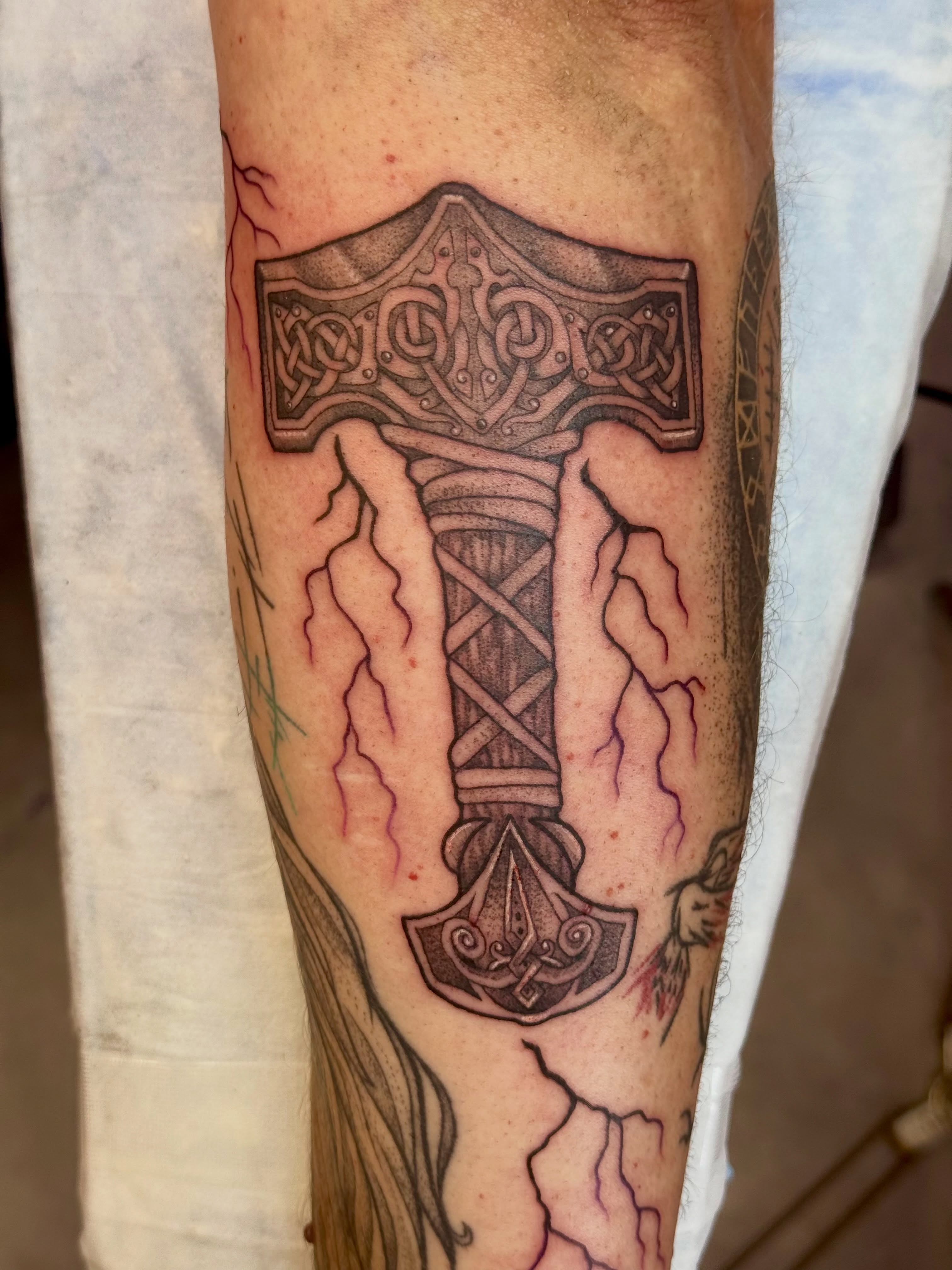 Mjolnir black and grey tattoo on the forearm by Caitlynn Austin