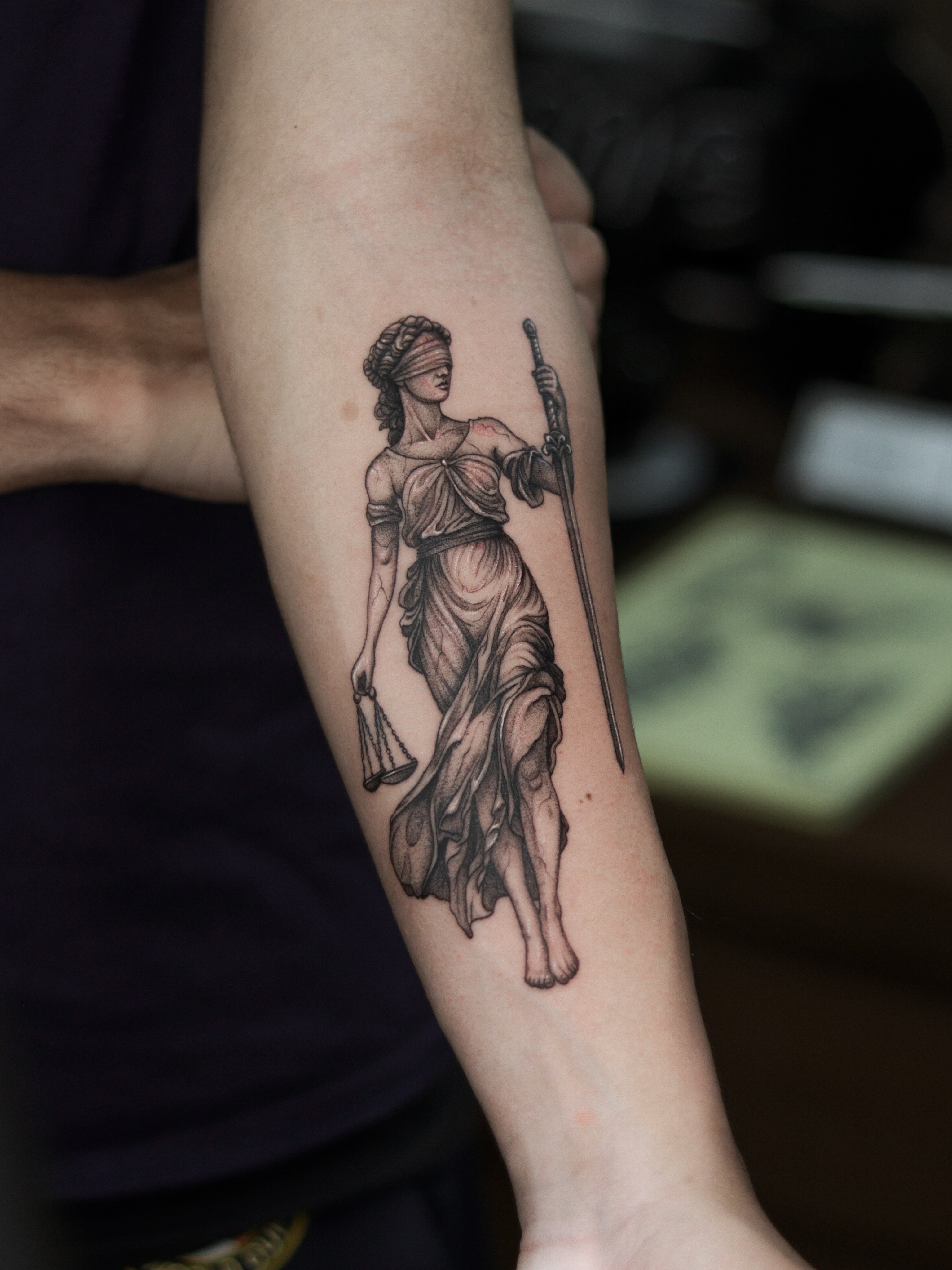 Statue of lady justice black and grey tattoo on the forearm by Arthur Kossoski