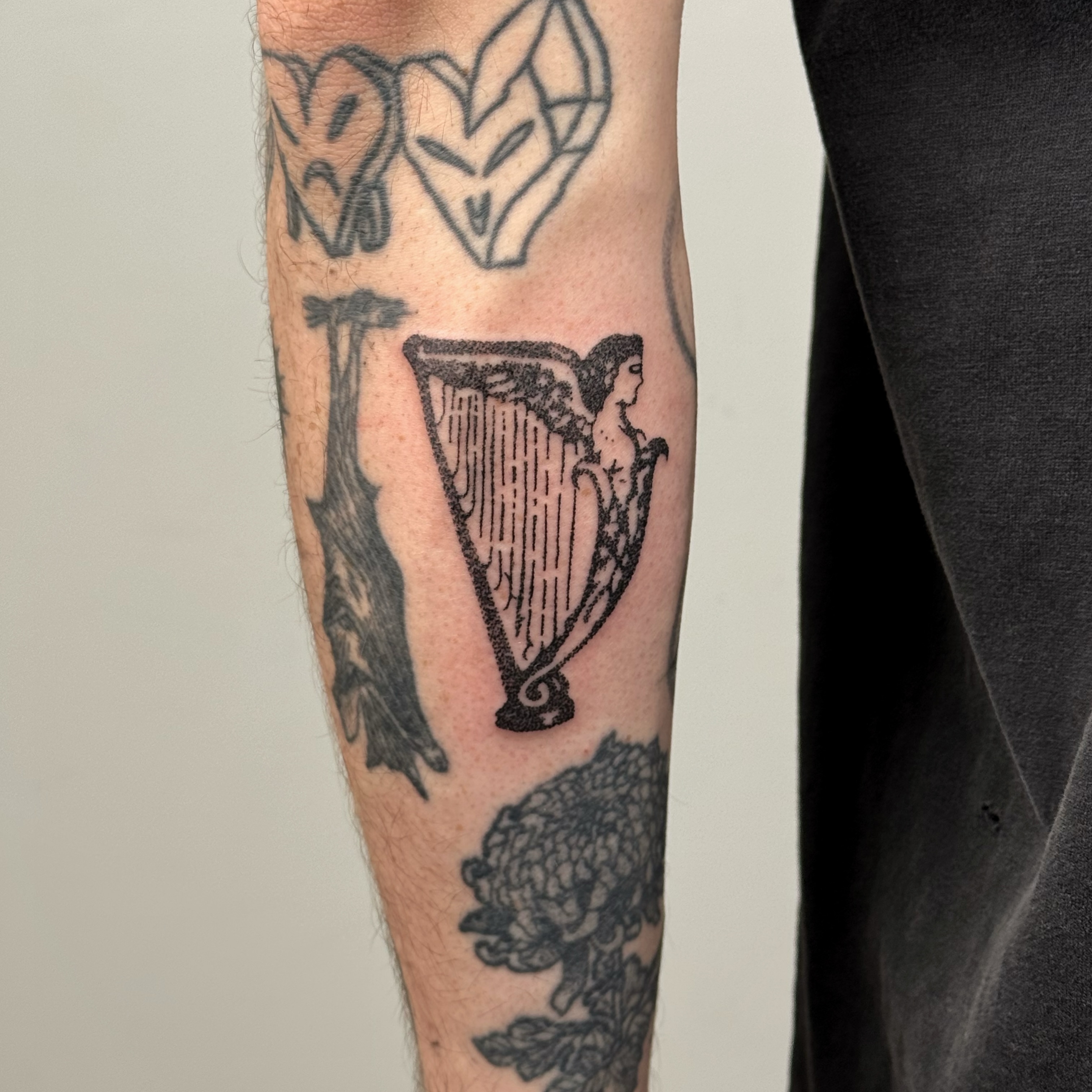 Harp black and grey tattoo on the forearm by Joint Killer
