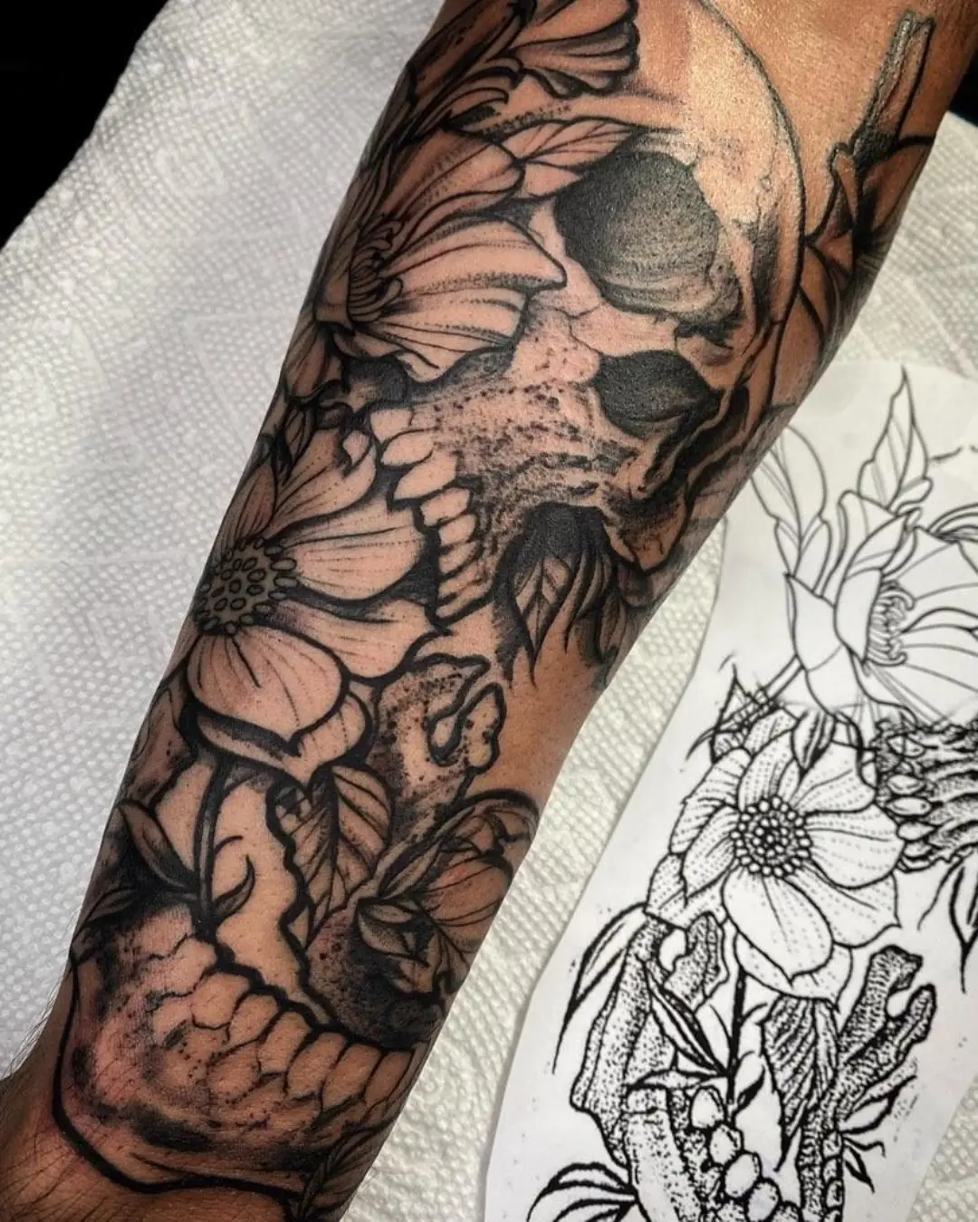 Skull with floral elements realism tattoo on the forearm by @inkhazmat