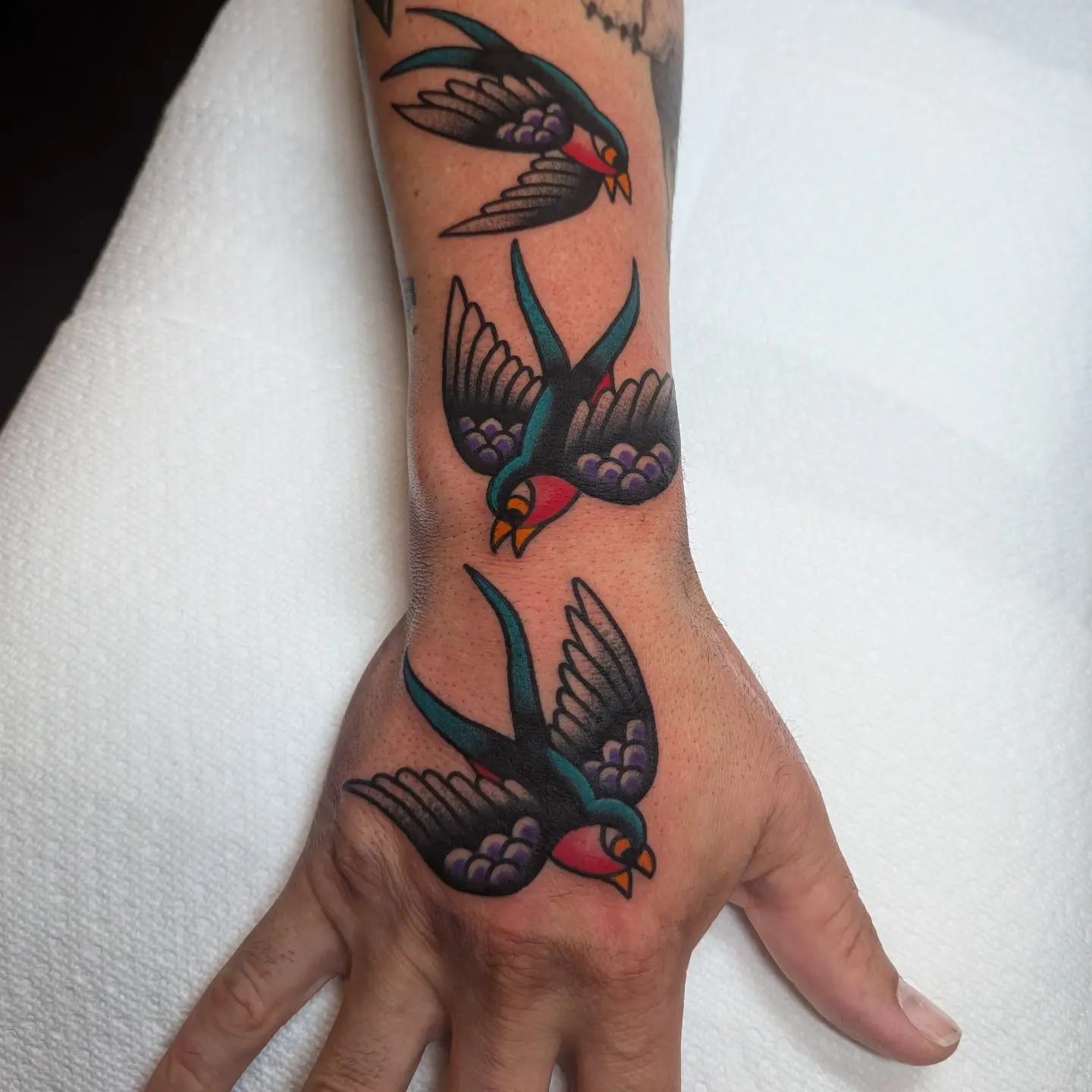 Swallows American traditional tattoo on the hand by Zack Mueller