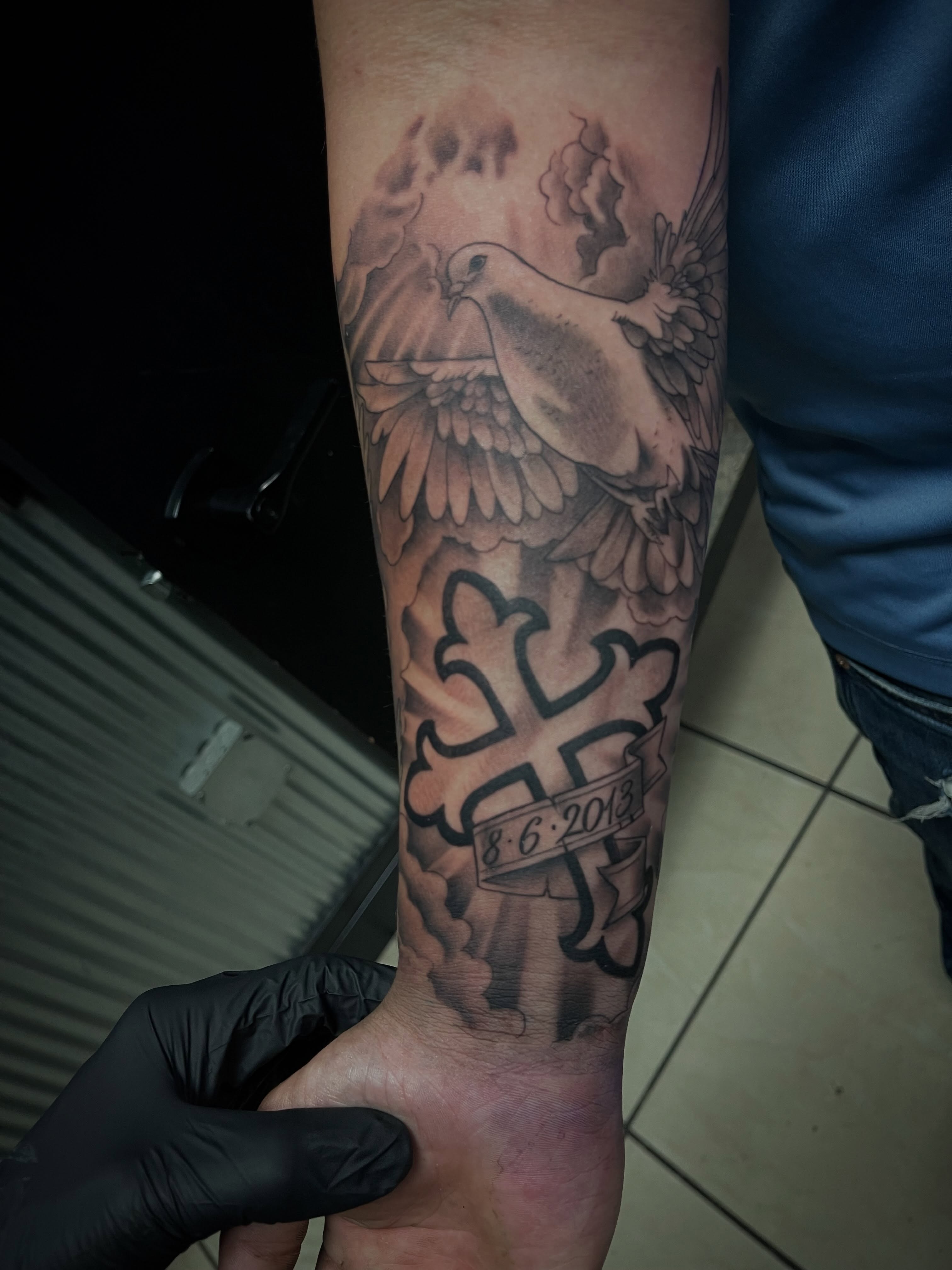 Cross with dove black and grey tattoo on the forearm by Chris Torres