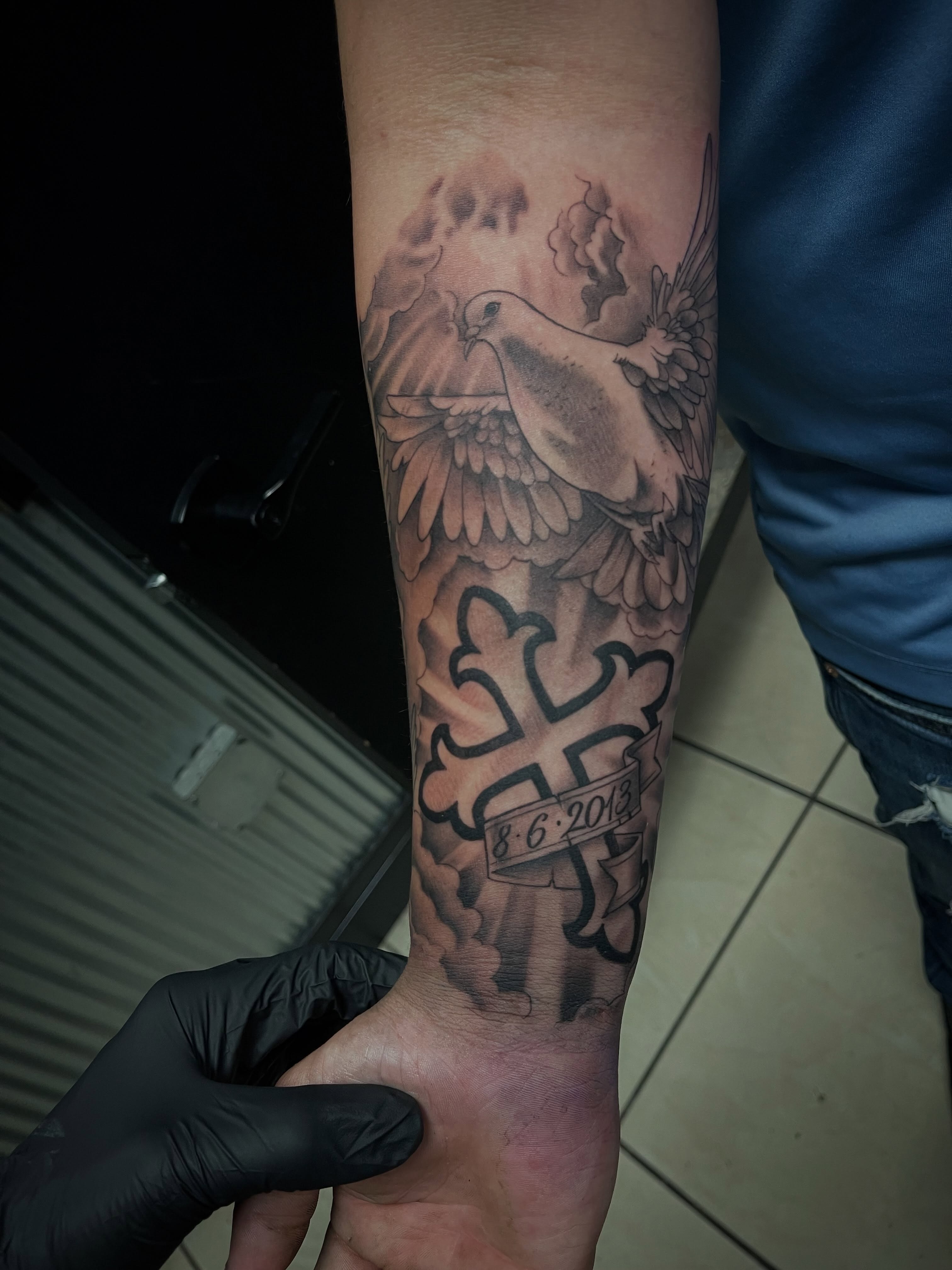 Dove and cross black and grey tattoo on the forearm by Chris Torres