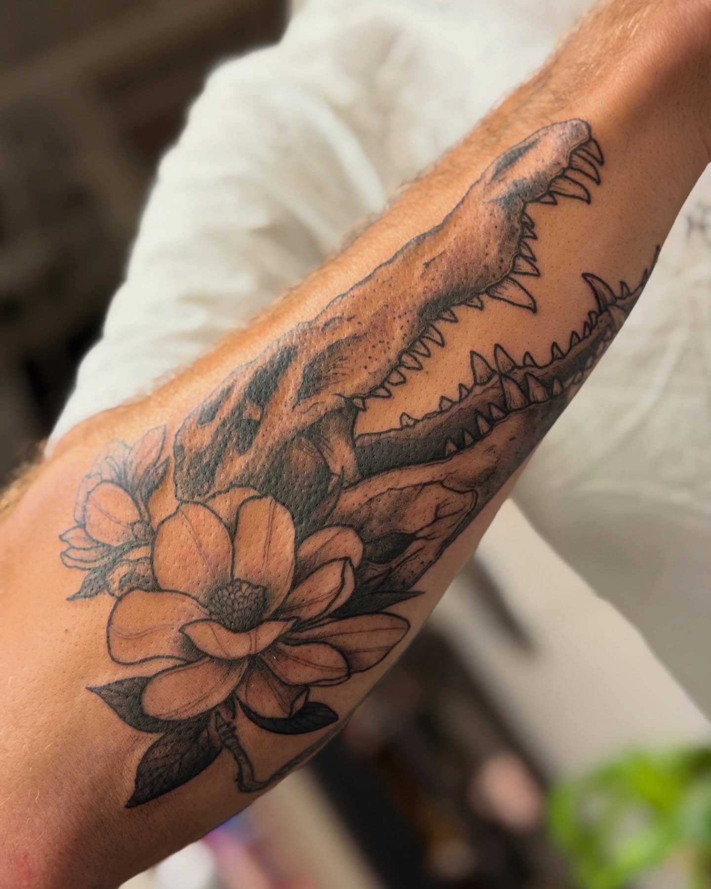 Dinosaur and flower black and grey tattoo on the forearm by Classy Fucking Lady Tattooer