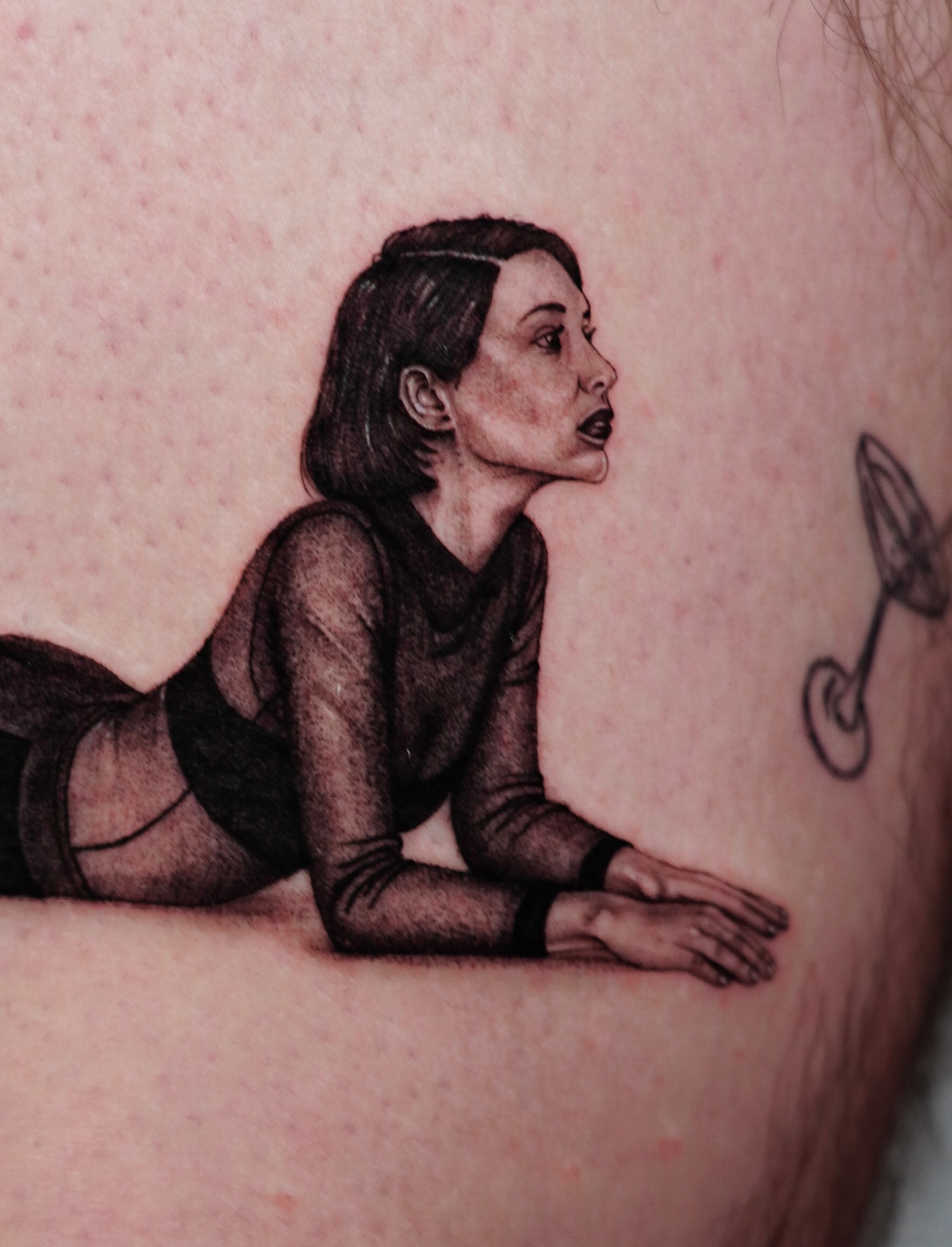 Woman lying down realism tattoo on the upper arm by Sophia Delfino
