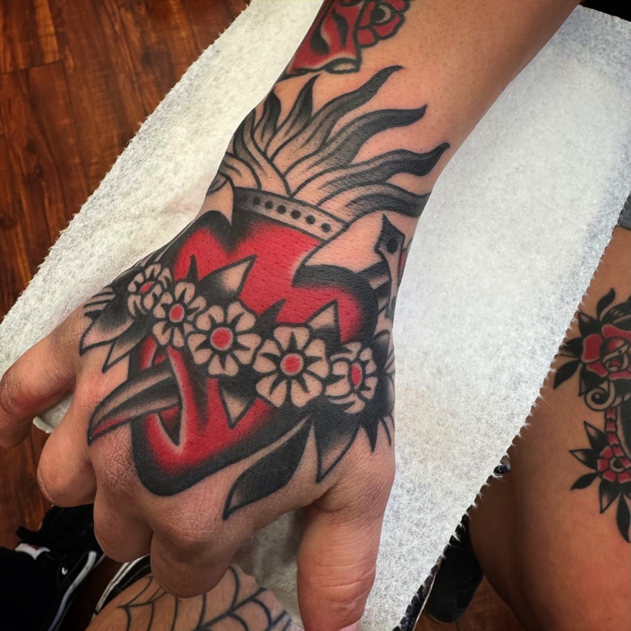 Heart with crown and flowers American traditional tattoo on the hand by Rogelio Robles