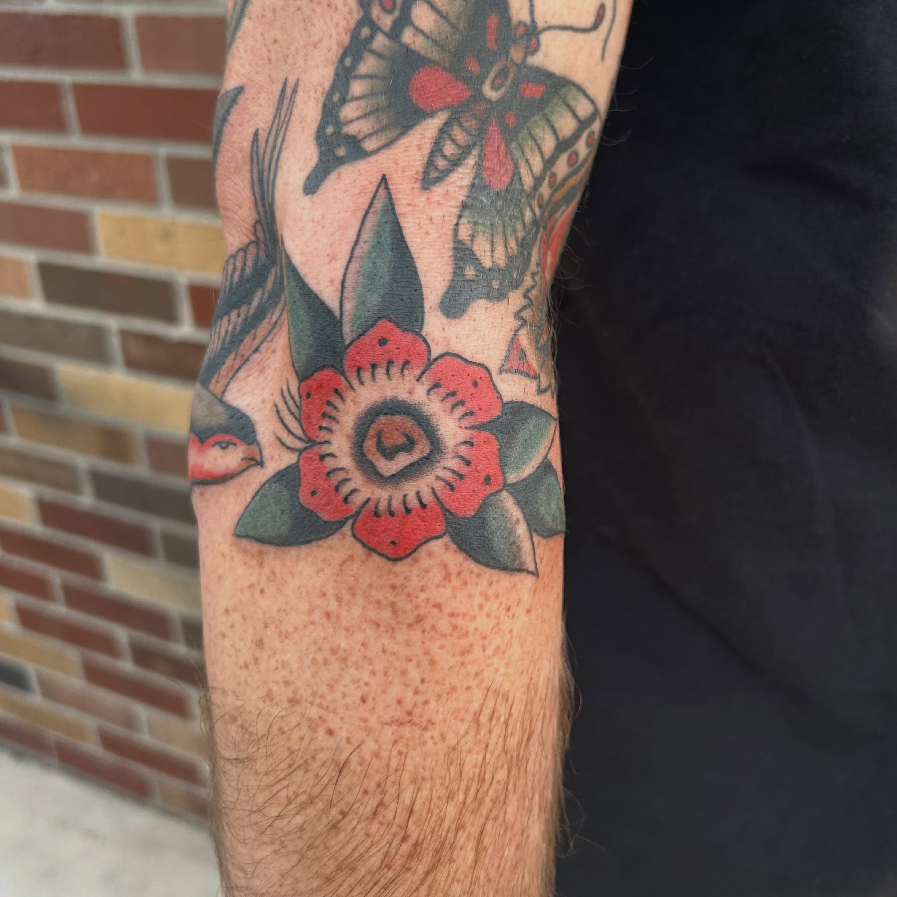 Flower and butterflies American traditional tattoo on the forearm by Donny