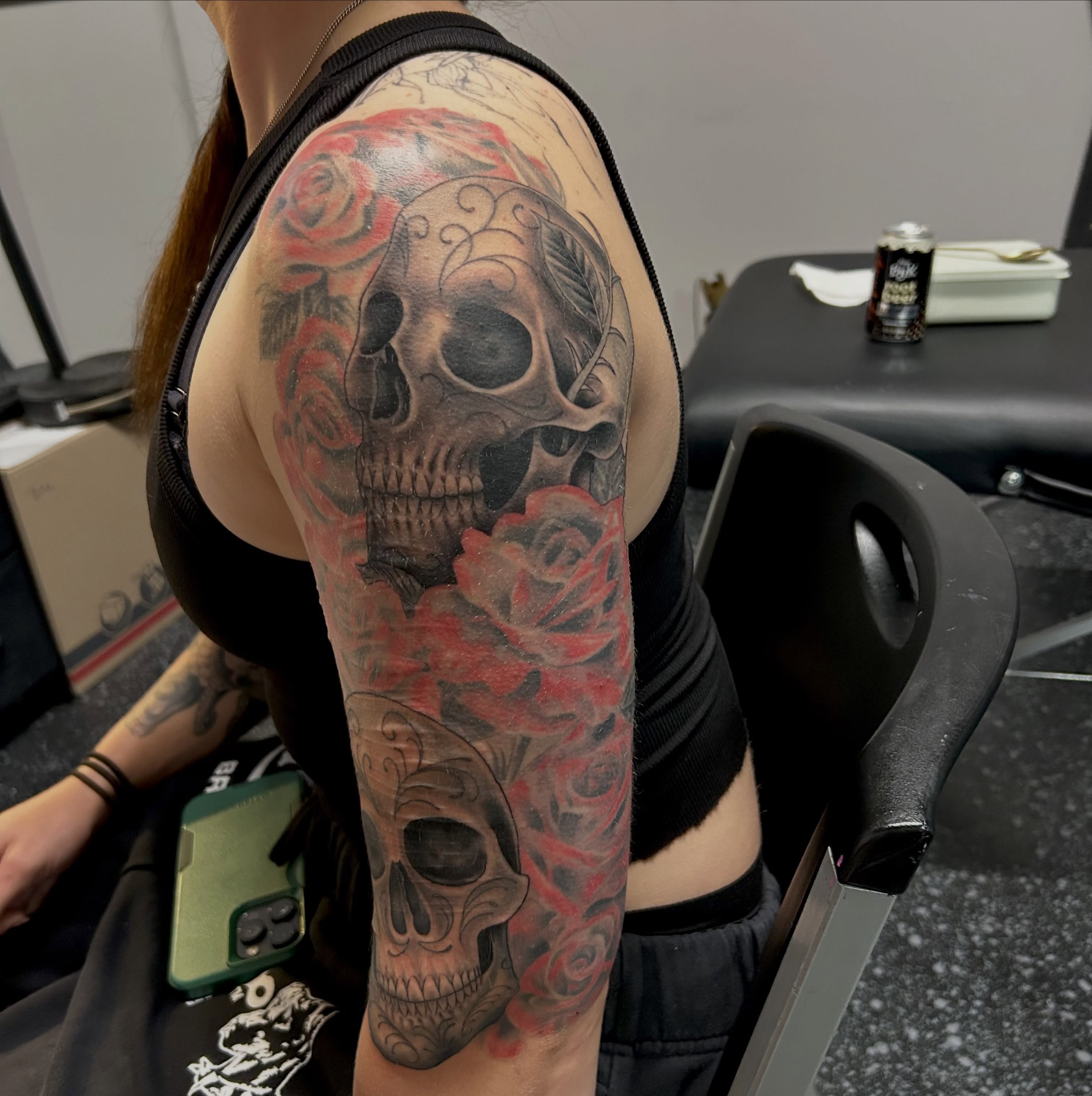Skulls and roses realism tattoo on the upper arm by Jamie Winn