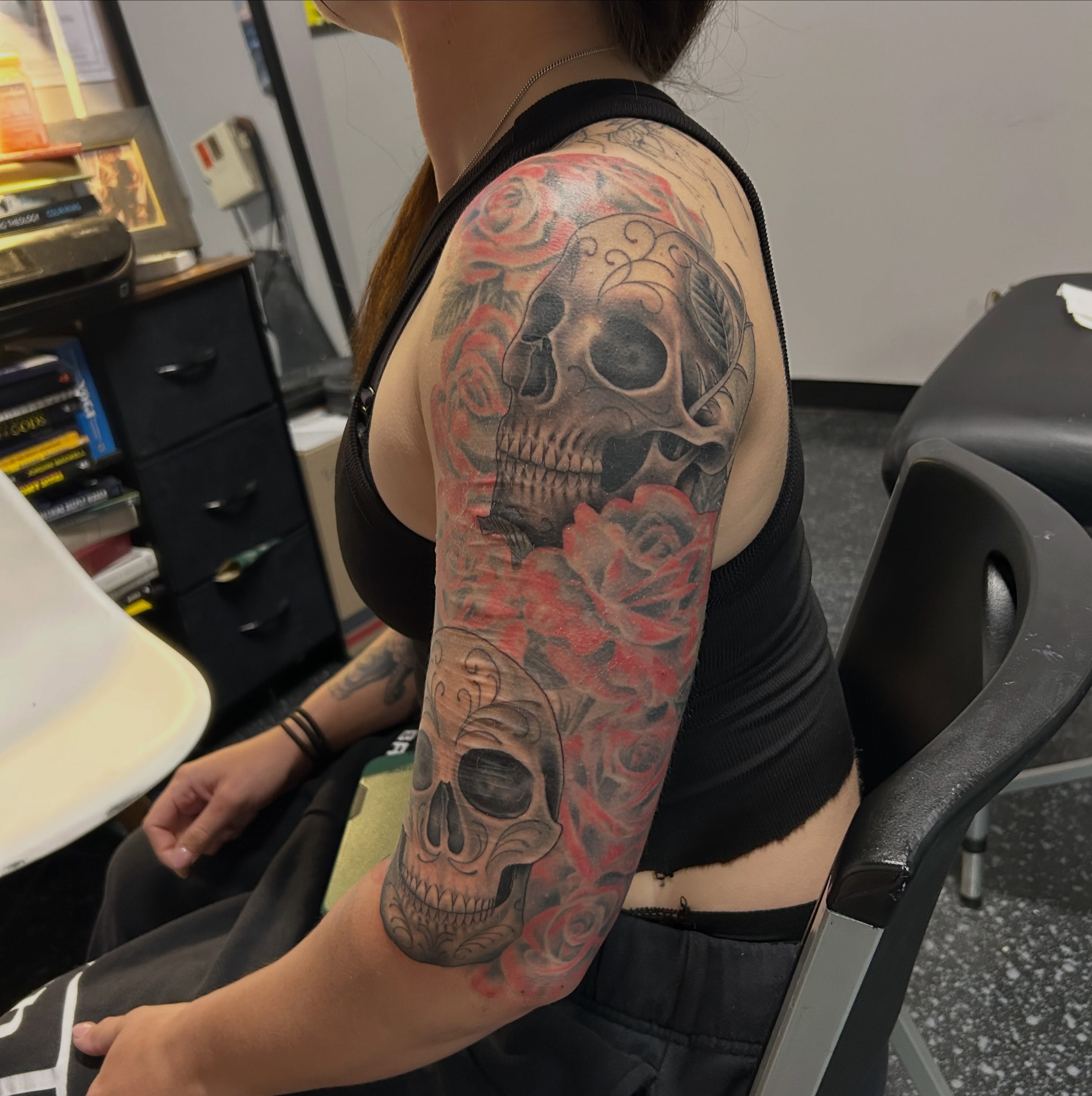 Skulls and roses realism tattoo on the upper arm by Jamie Winn