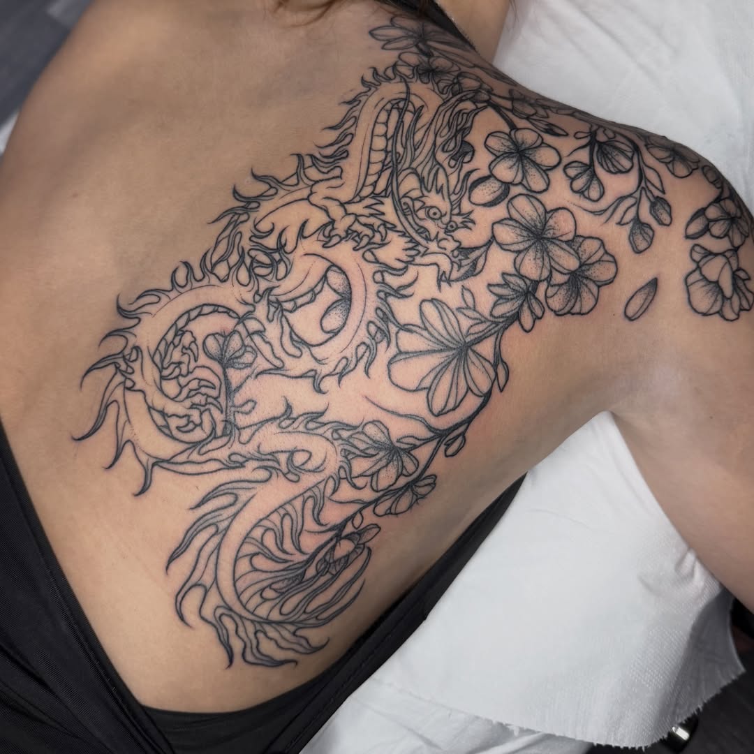 Dragon and flowers black and grey tattoo on the shoulder by Aiden Shaw