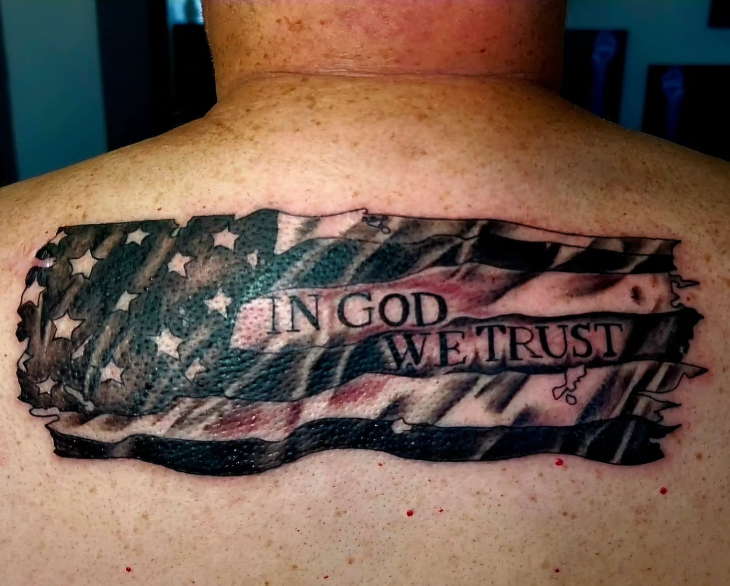 American flag and 'in god we trust' American traditional tattoo on the back by Captain Michael Devious