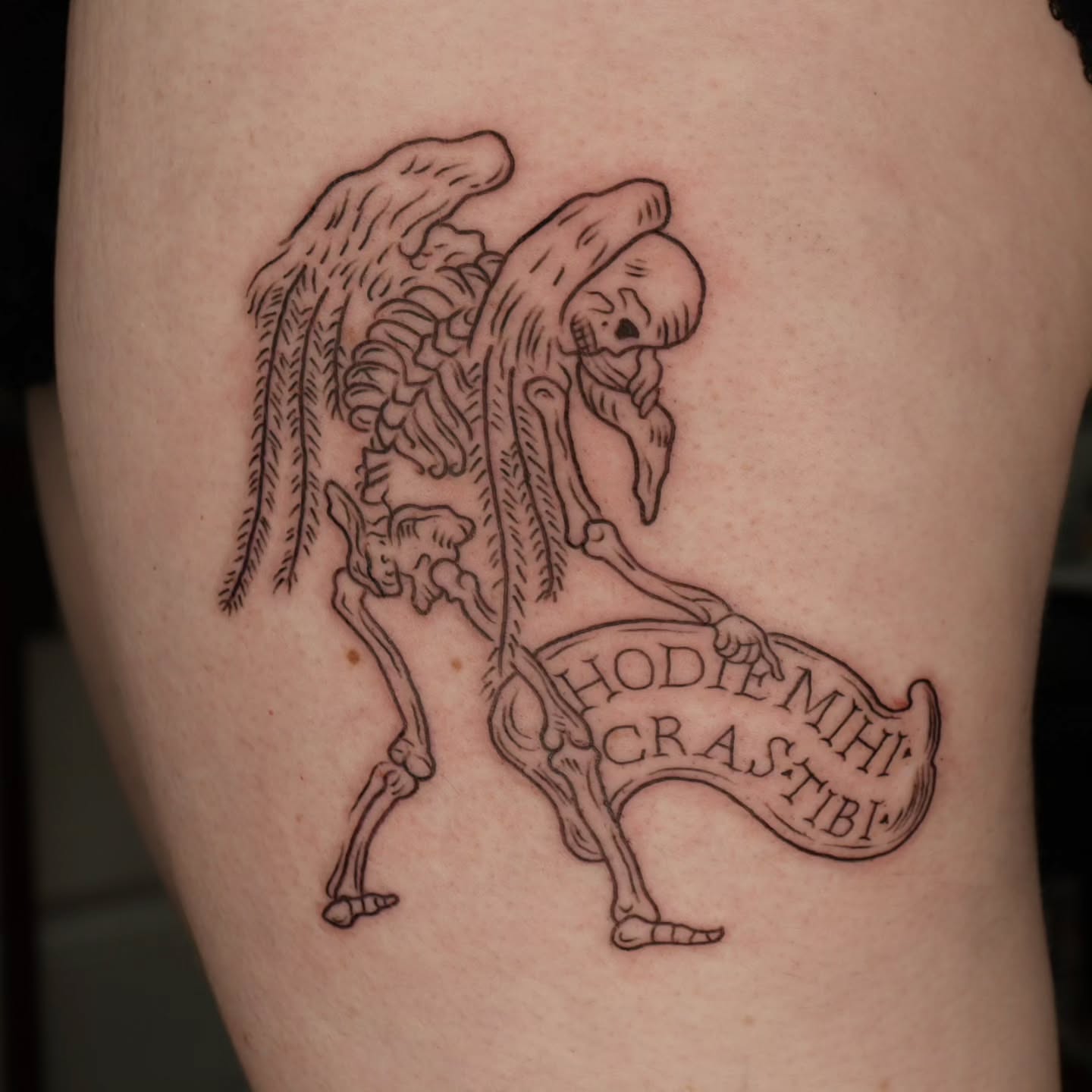 Skeleton with banner black and grey tattoo on the thigh by Veronika Lipchak