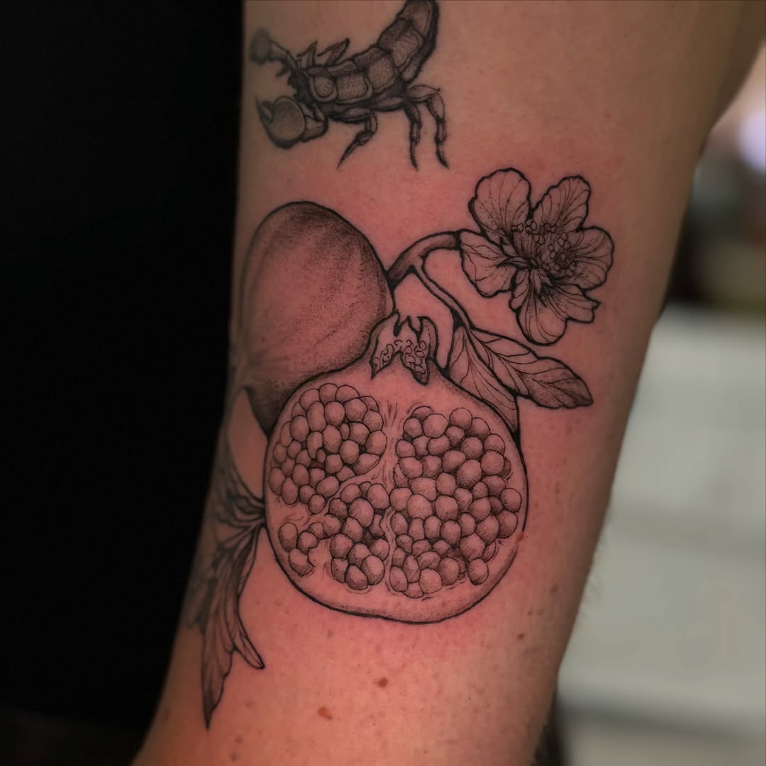 Pomegranate and flower realism tattoo on the forearm by Chloe Shay