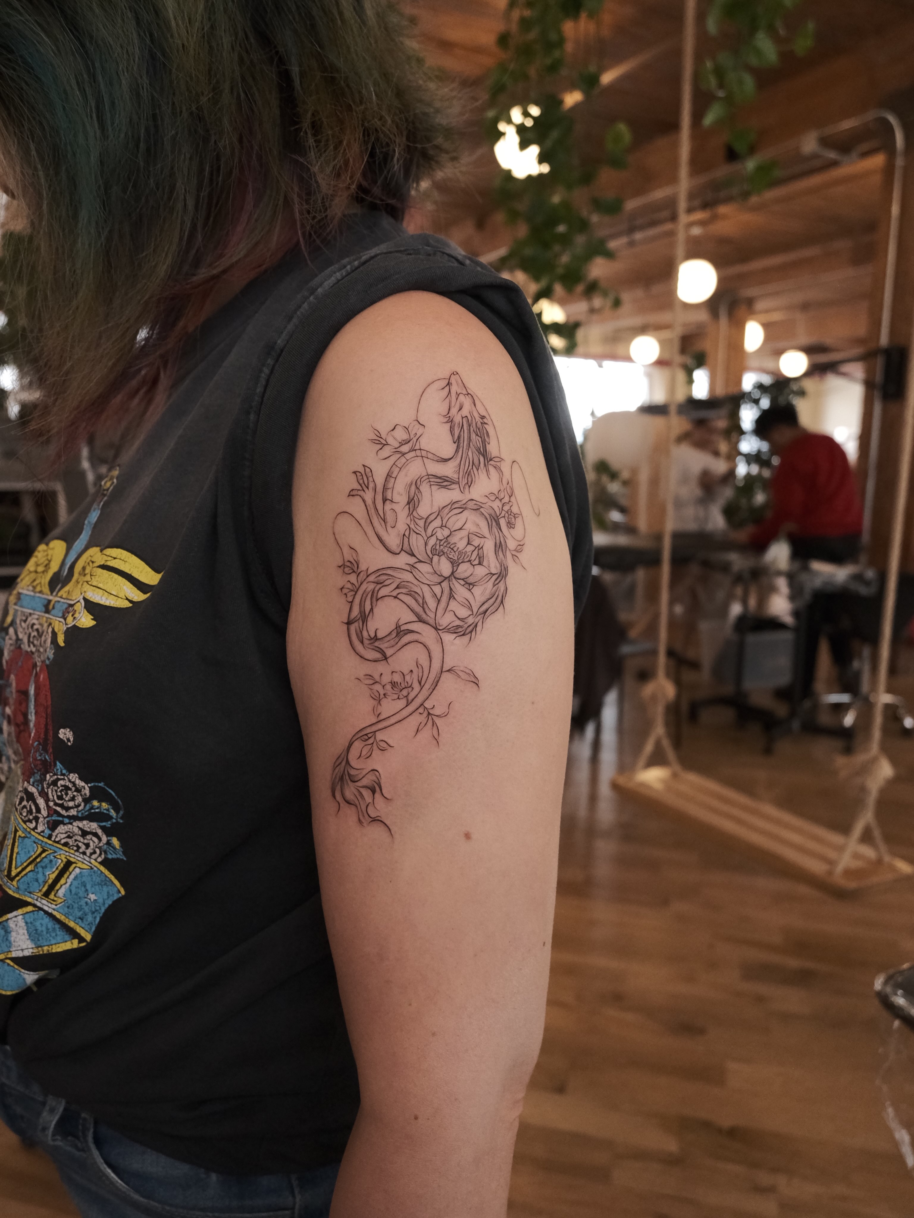 Dragon and lotus black and grey tattoo on the upper arm by Ethan