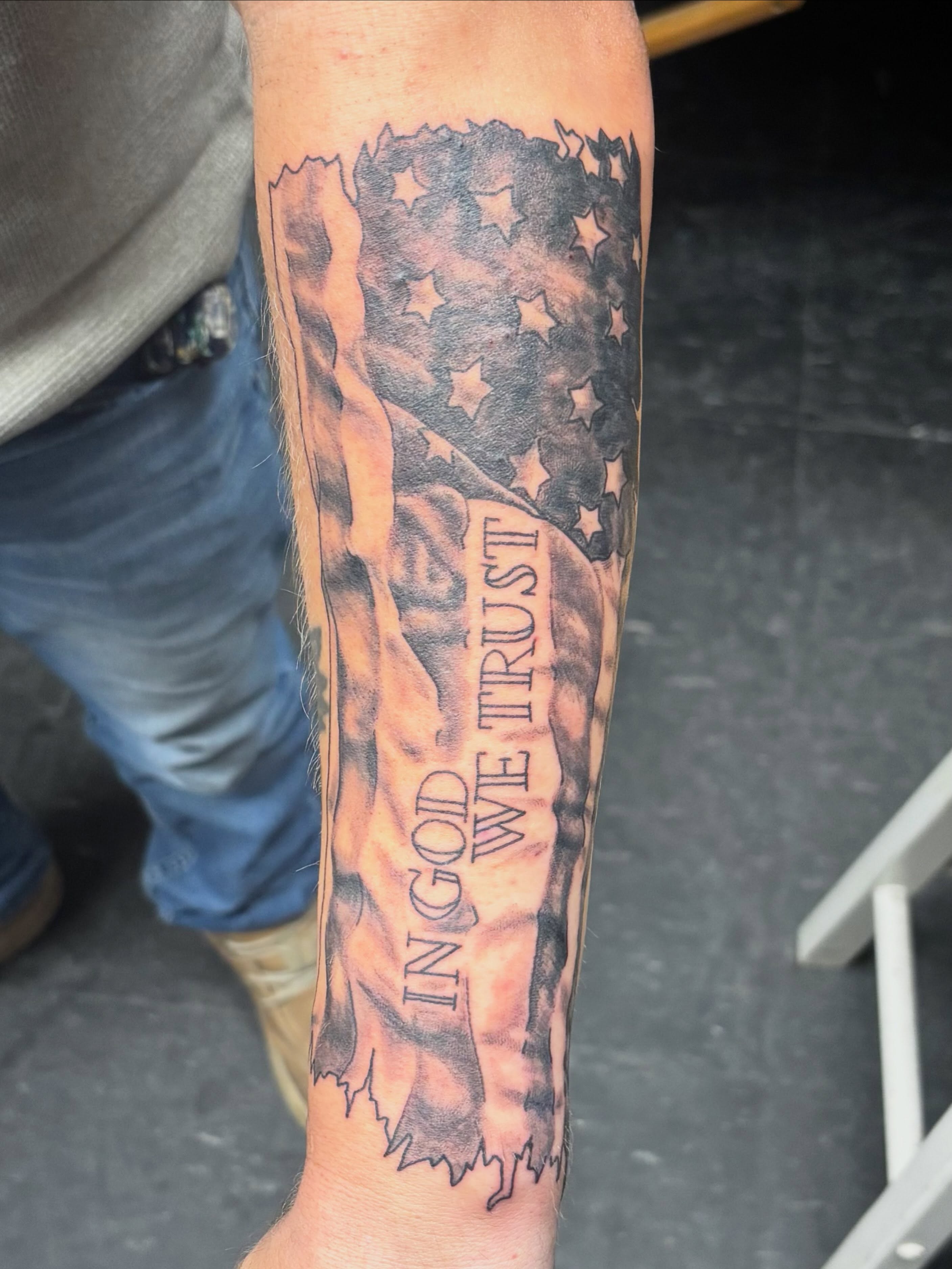 American flag black and grey tattoo on the forearm by Jeff Zuptich