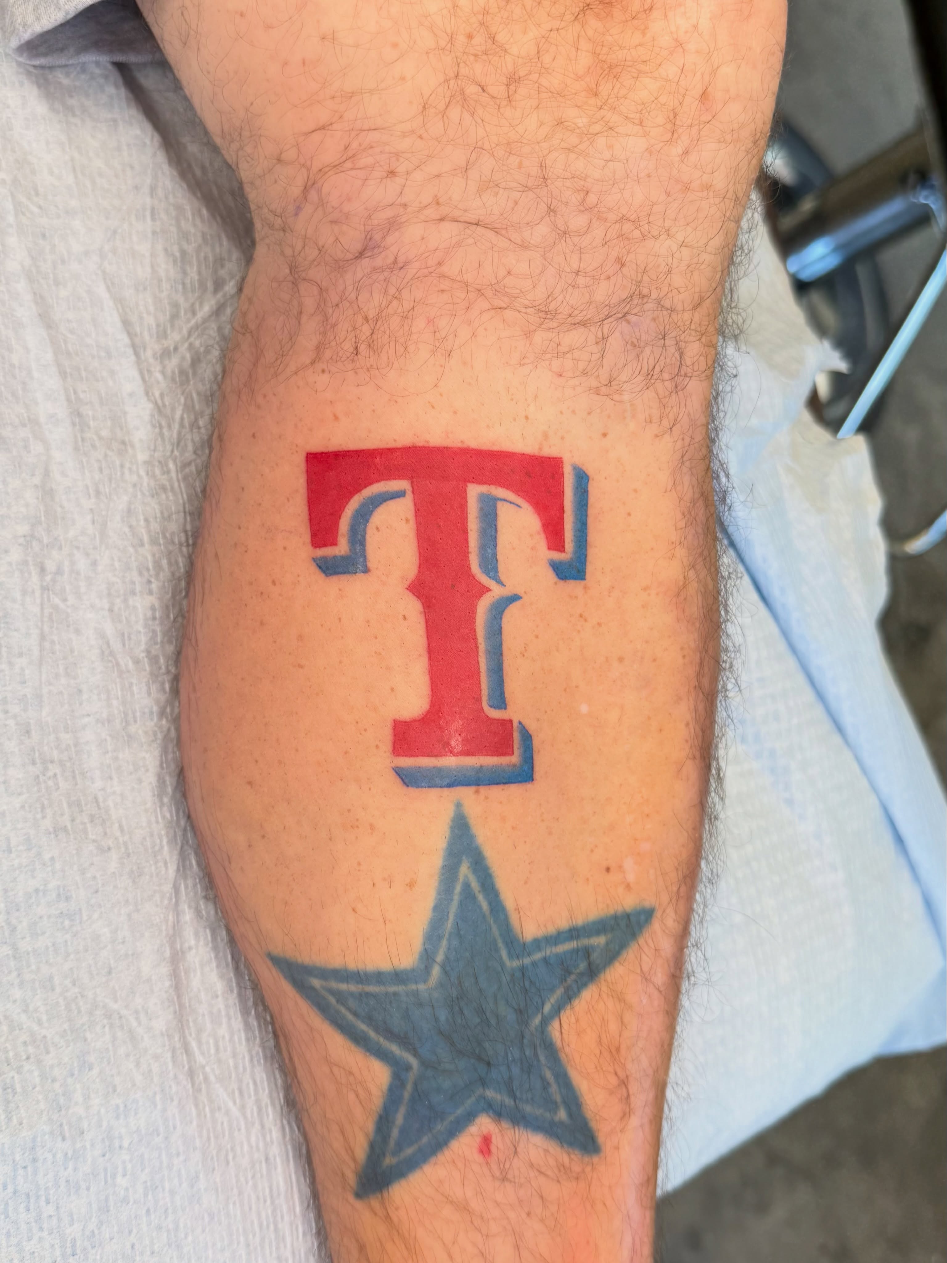 Red 'T' and blue star American traditional tattoo on the forearm by Ricky Sanchez, Duncanville, Texas
