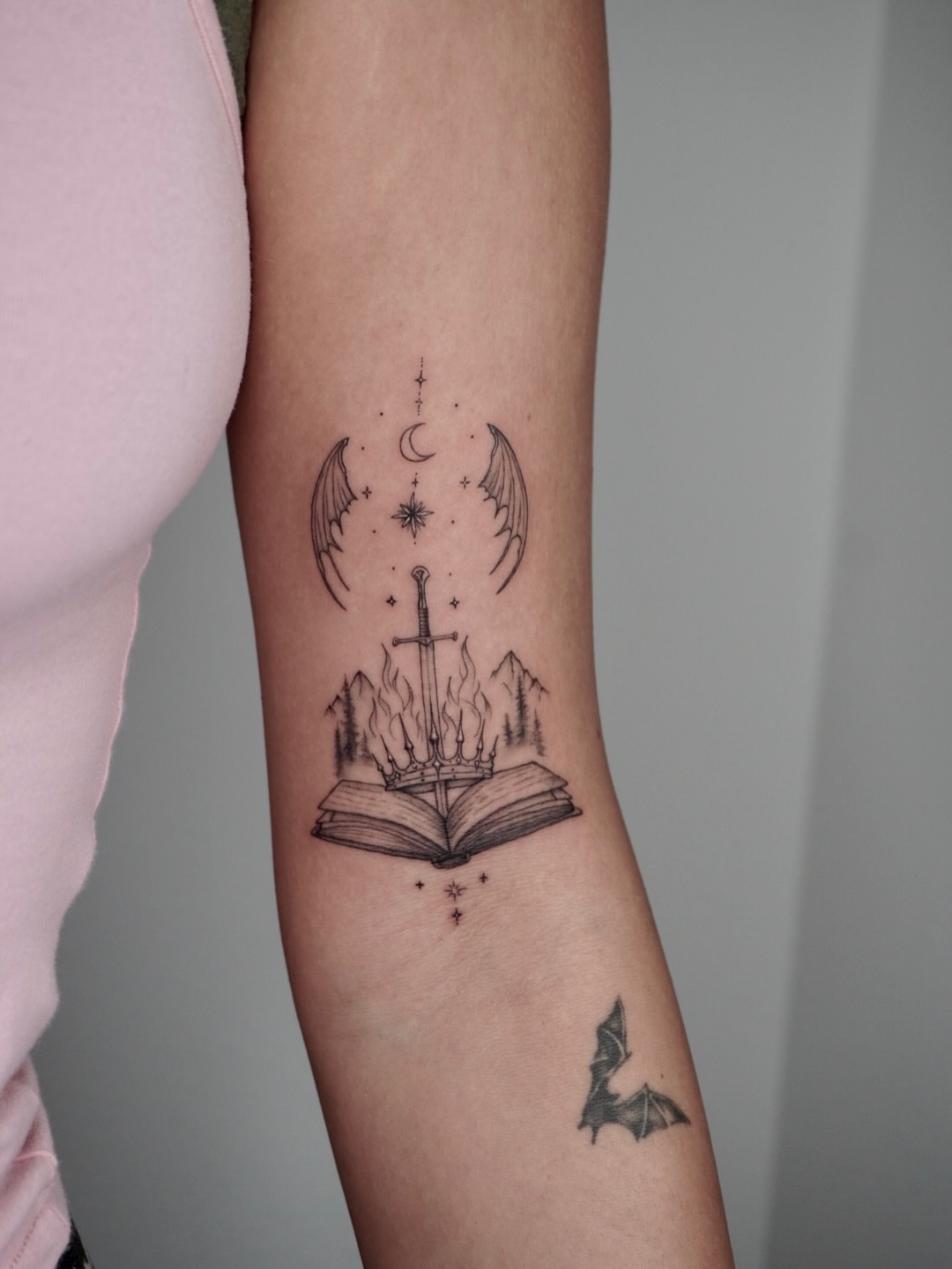 Book with sword and wings black and grey tattoo on the forearm by Ashley Limon
