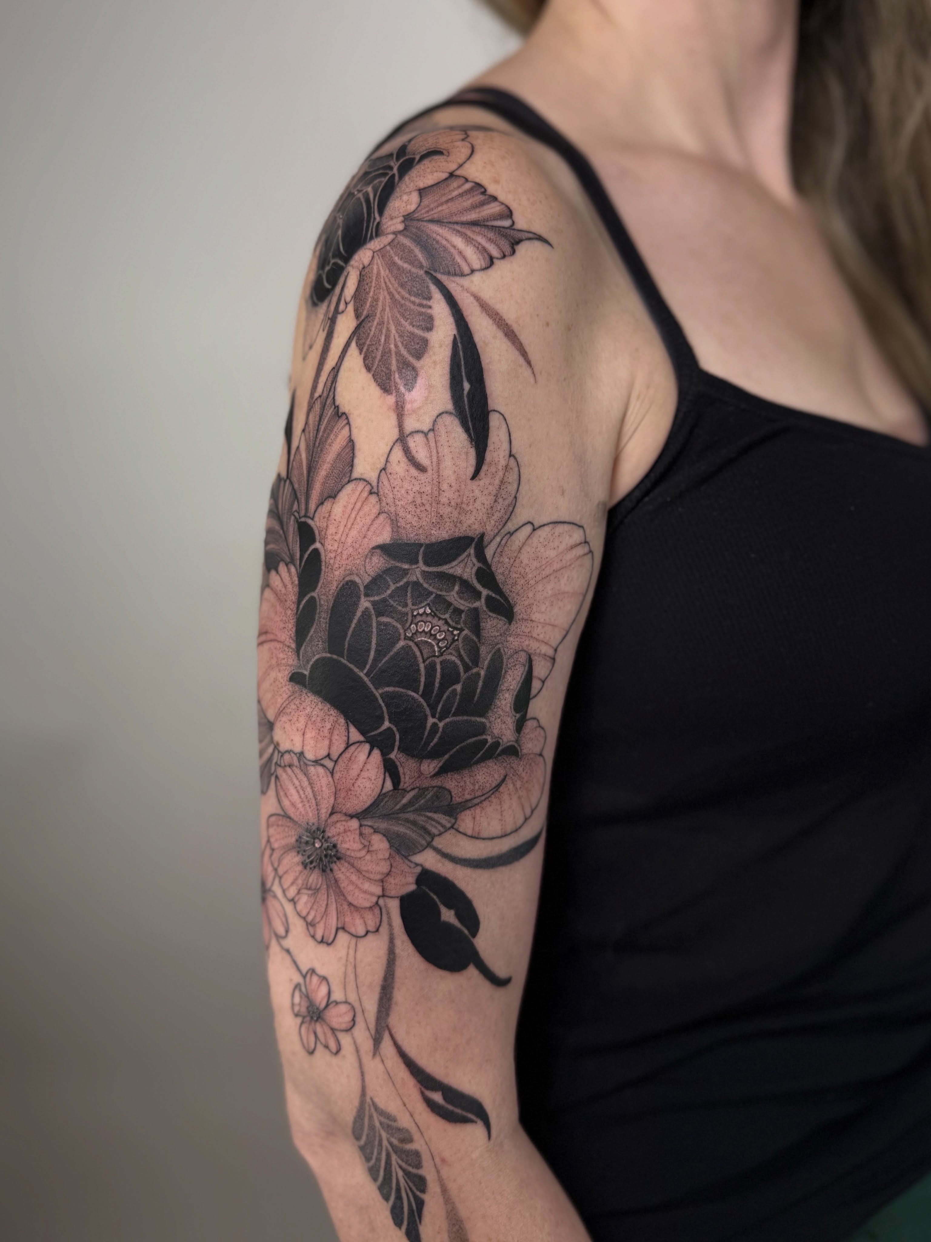 Floral arrangement black and grey tattoo on the upper arm by Jena Perry