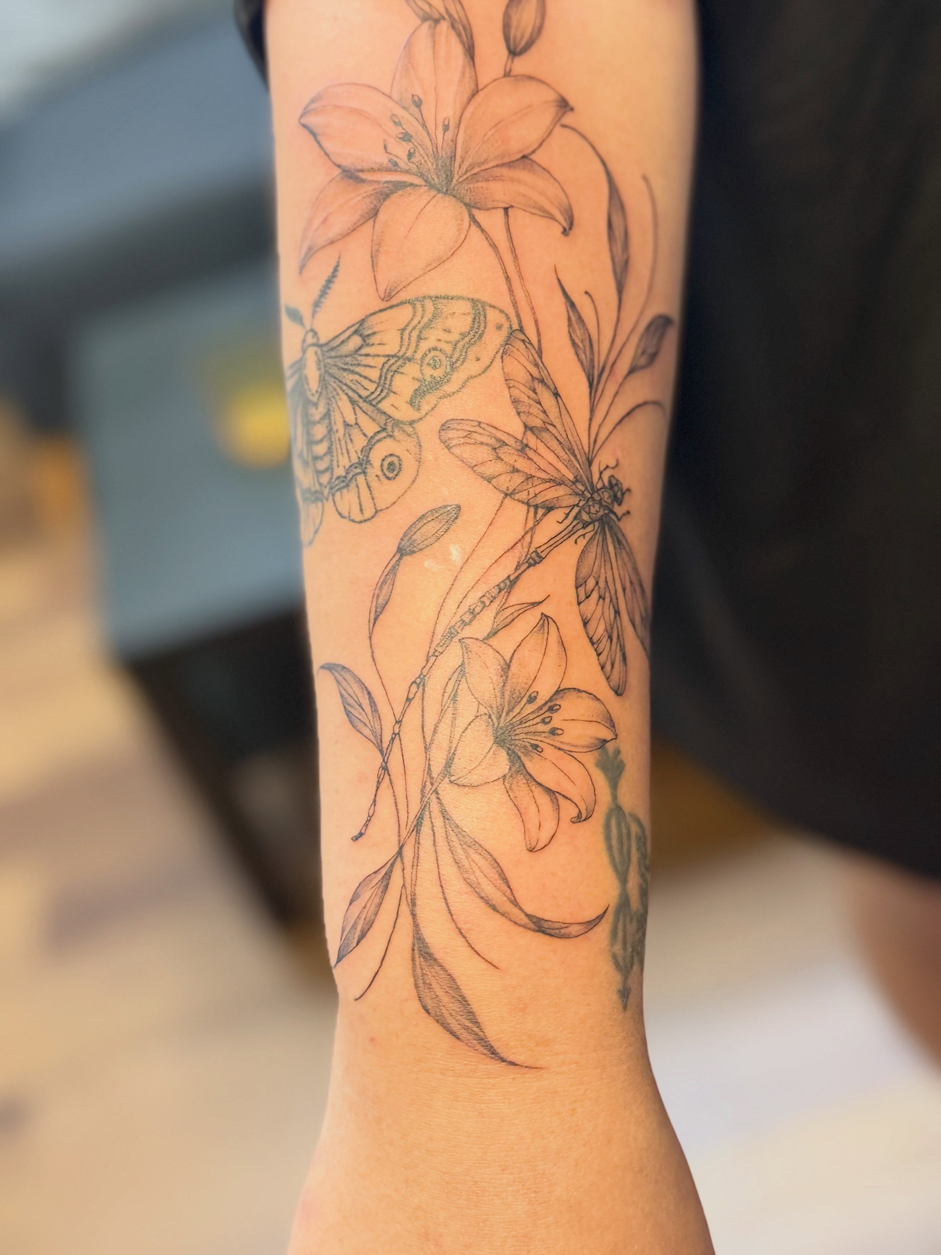 Lilies and insects realism tattoo on the forearm by Tetiana