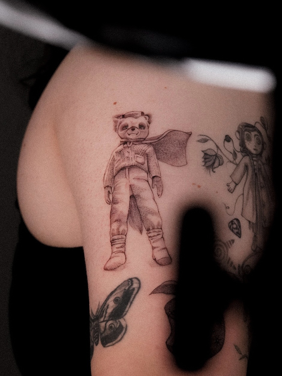 Superhero teddy bear black and grey tattoo on the thigh by Joy Christiana