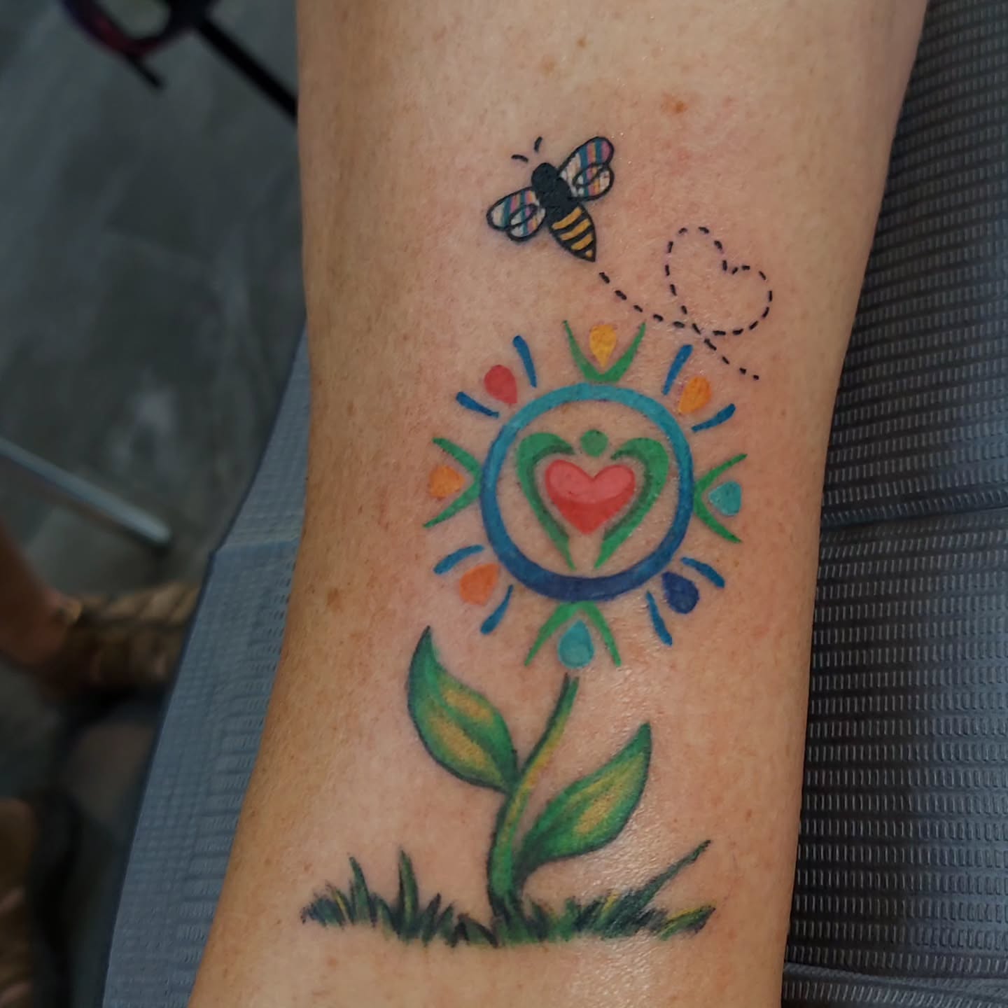 Flower with heart new school tattoo on the forearm by Kari Rhoades, Marion, Iowa