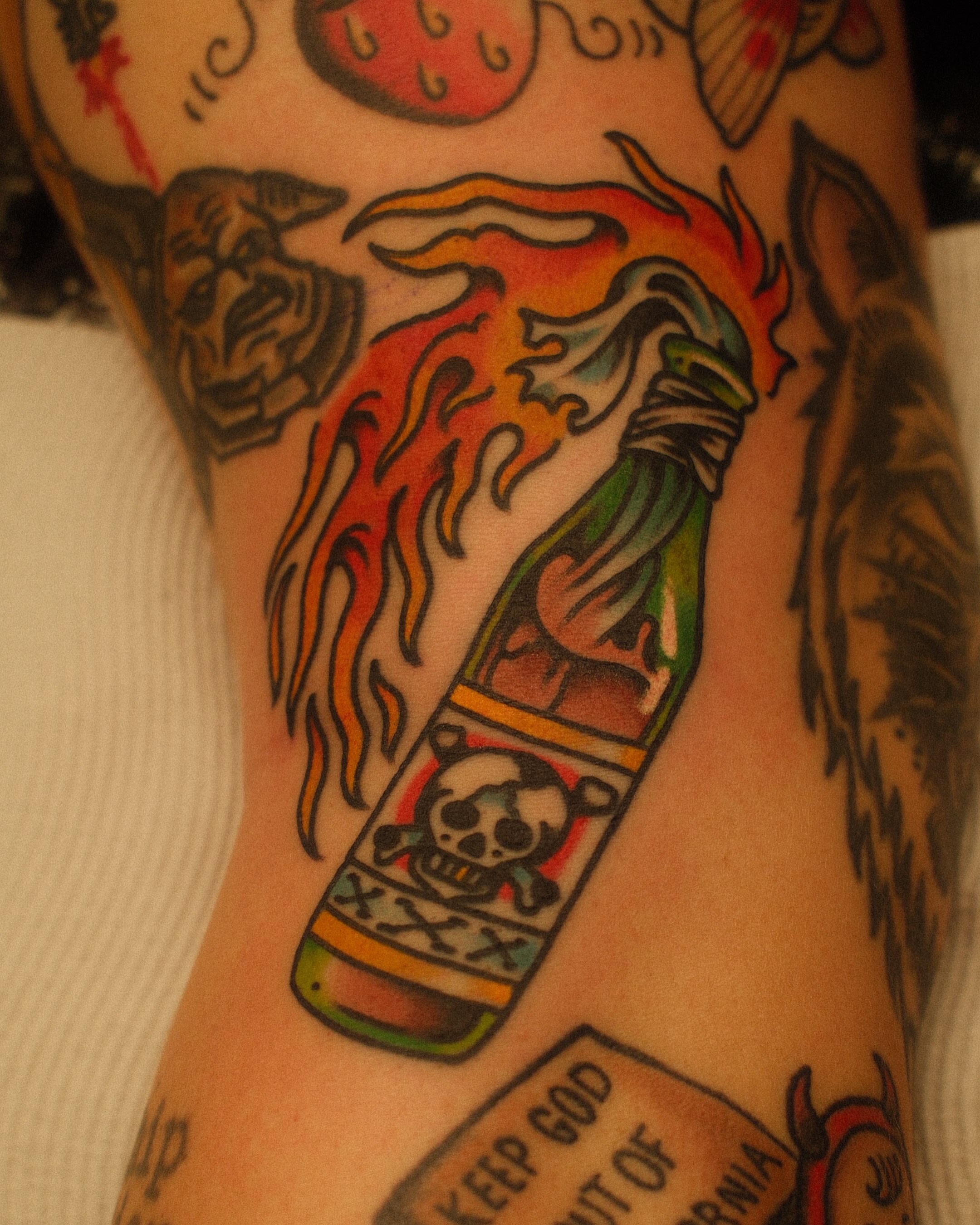Flaming bottle with skull American traditional tattoo on the forearm by Jonathan Clapp, San Antonio, Texas