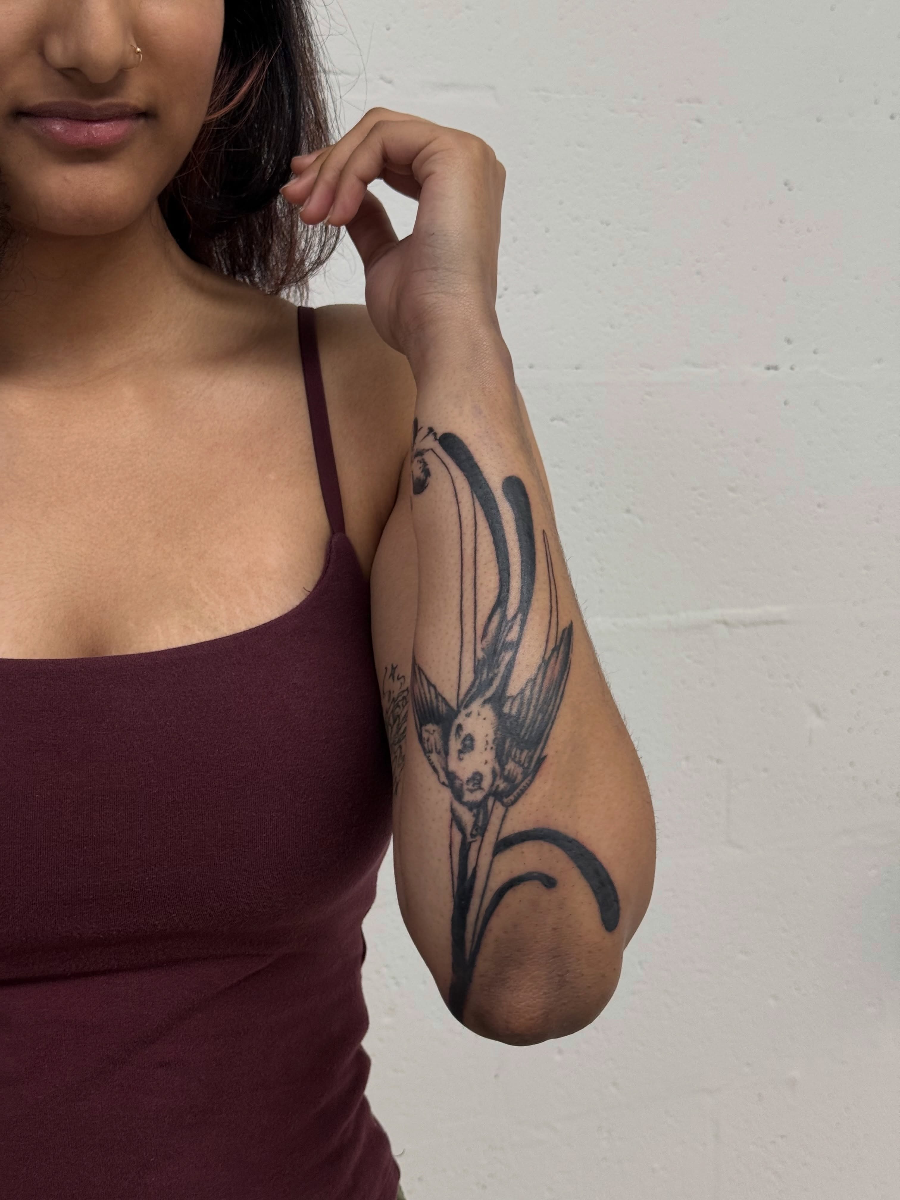 Bird and flower black and grey tattoo on the forearm by Ava Nilou