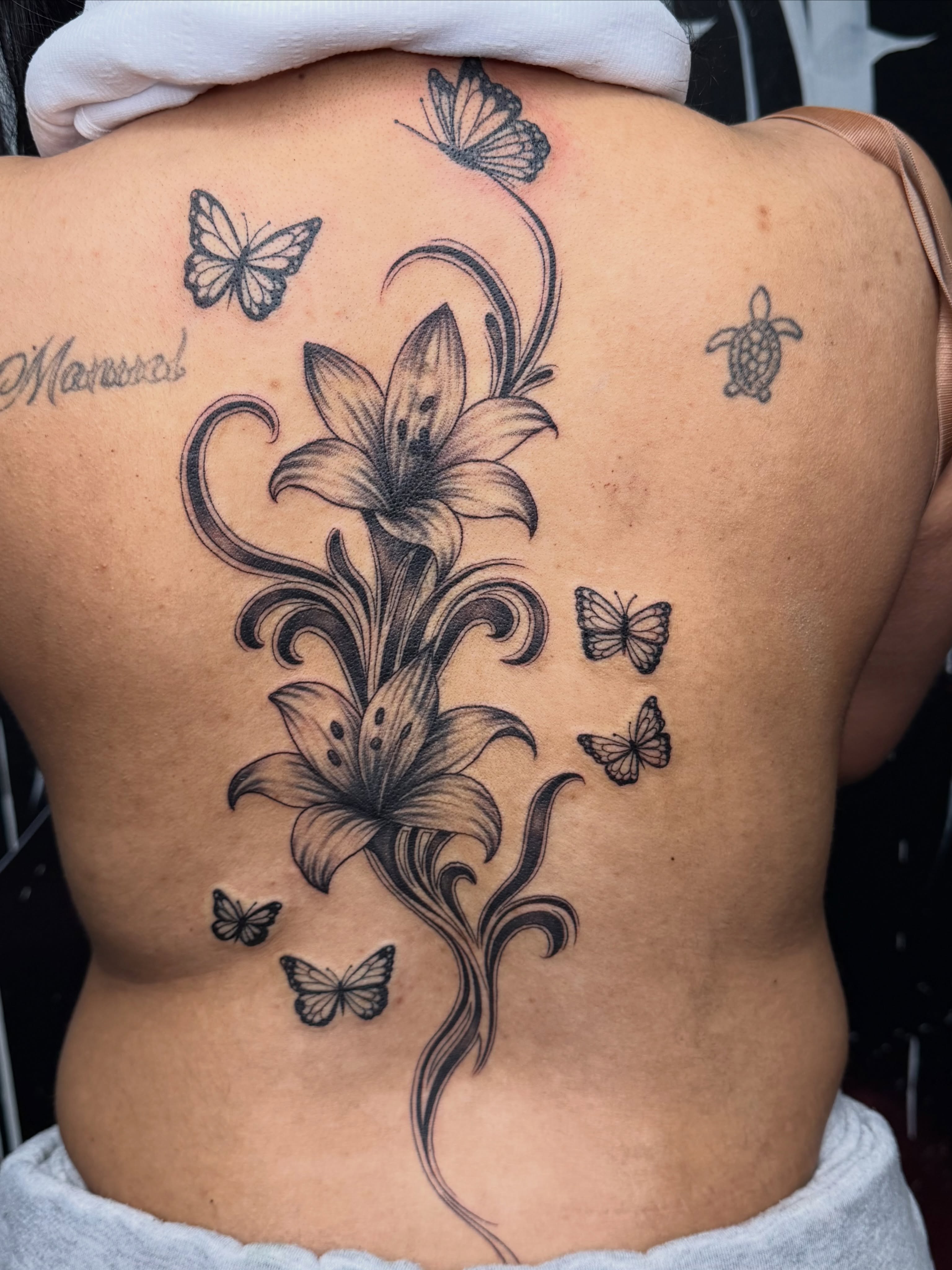 Lily and butterflies black and grey tattoo on the back by Kimberly landin