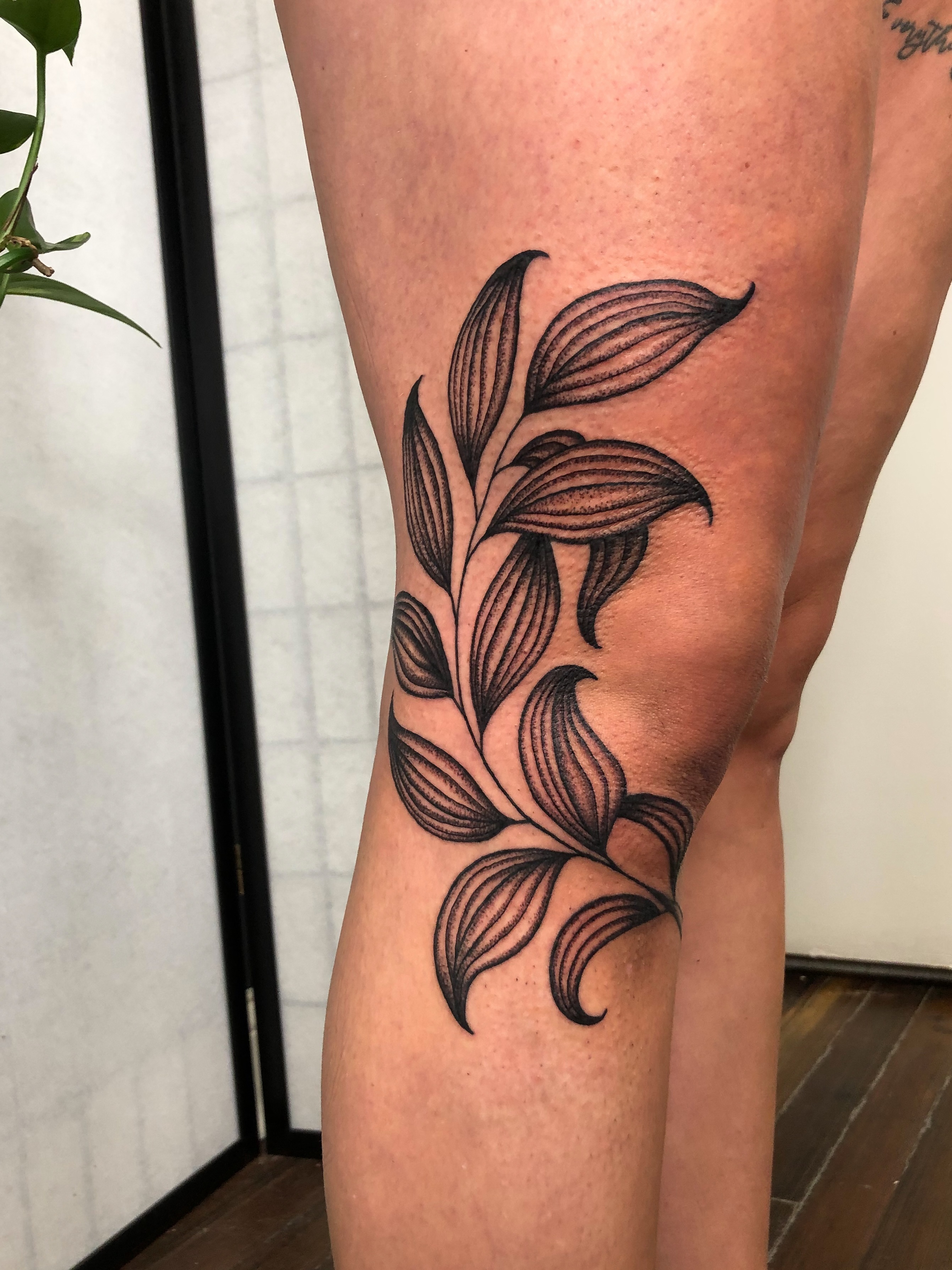Leaf black and grey tattoo on the thigh by Hannah Eddy