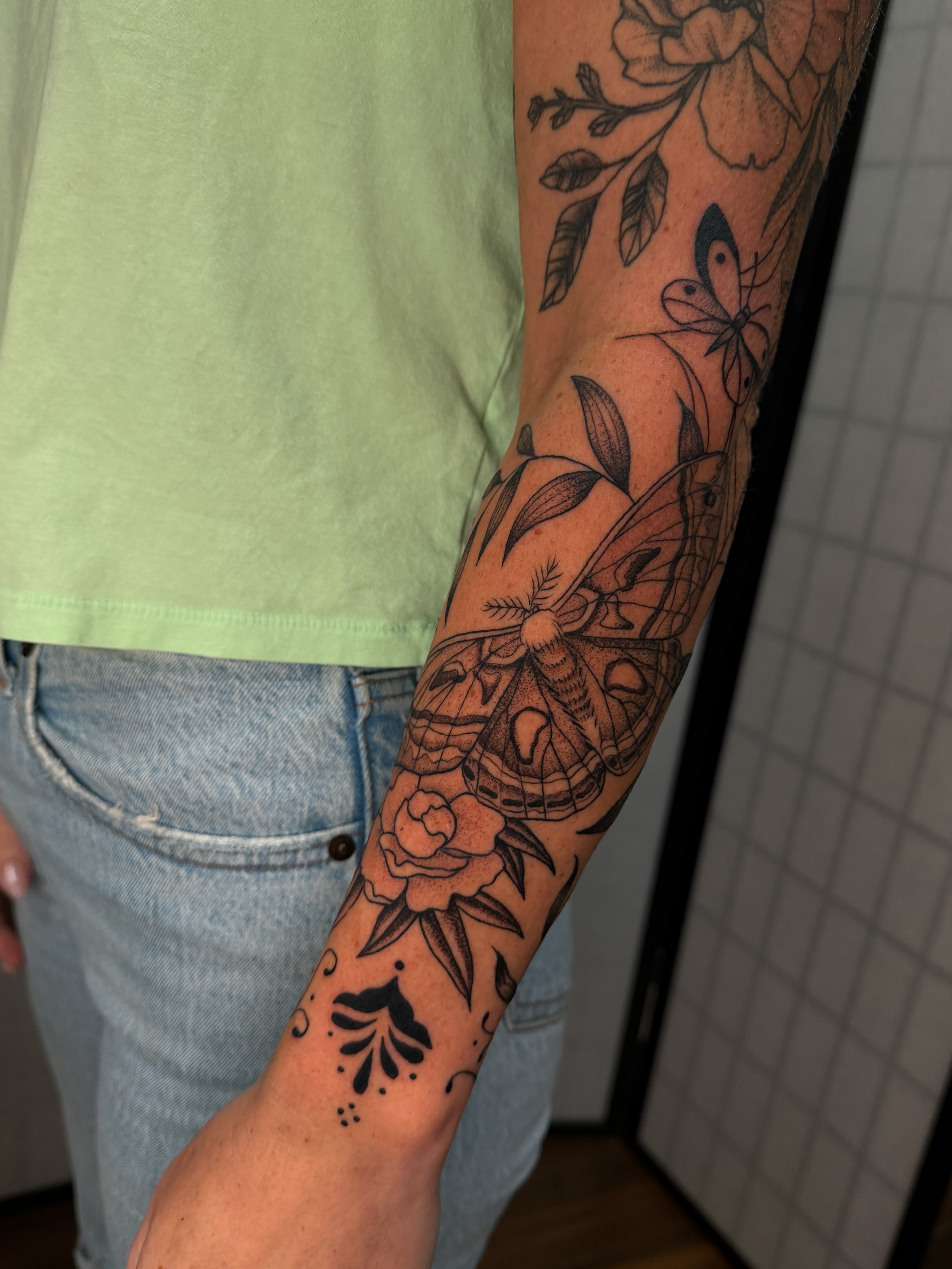 Butterfly and floral black and grey tattoo on the forearm by Hannah Eddy