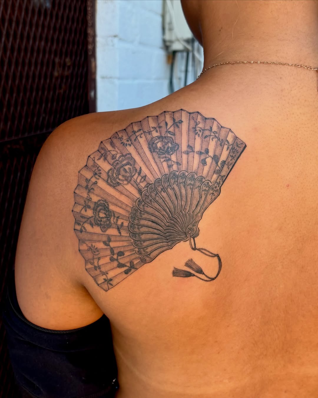 Fan black and grey tattoo on the back by Kylah Amin Tattoo