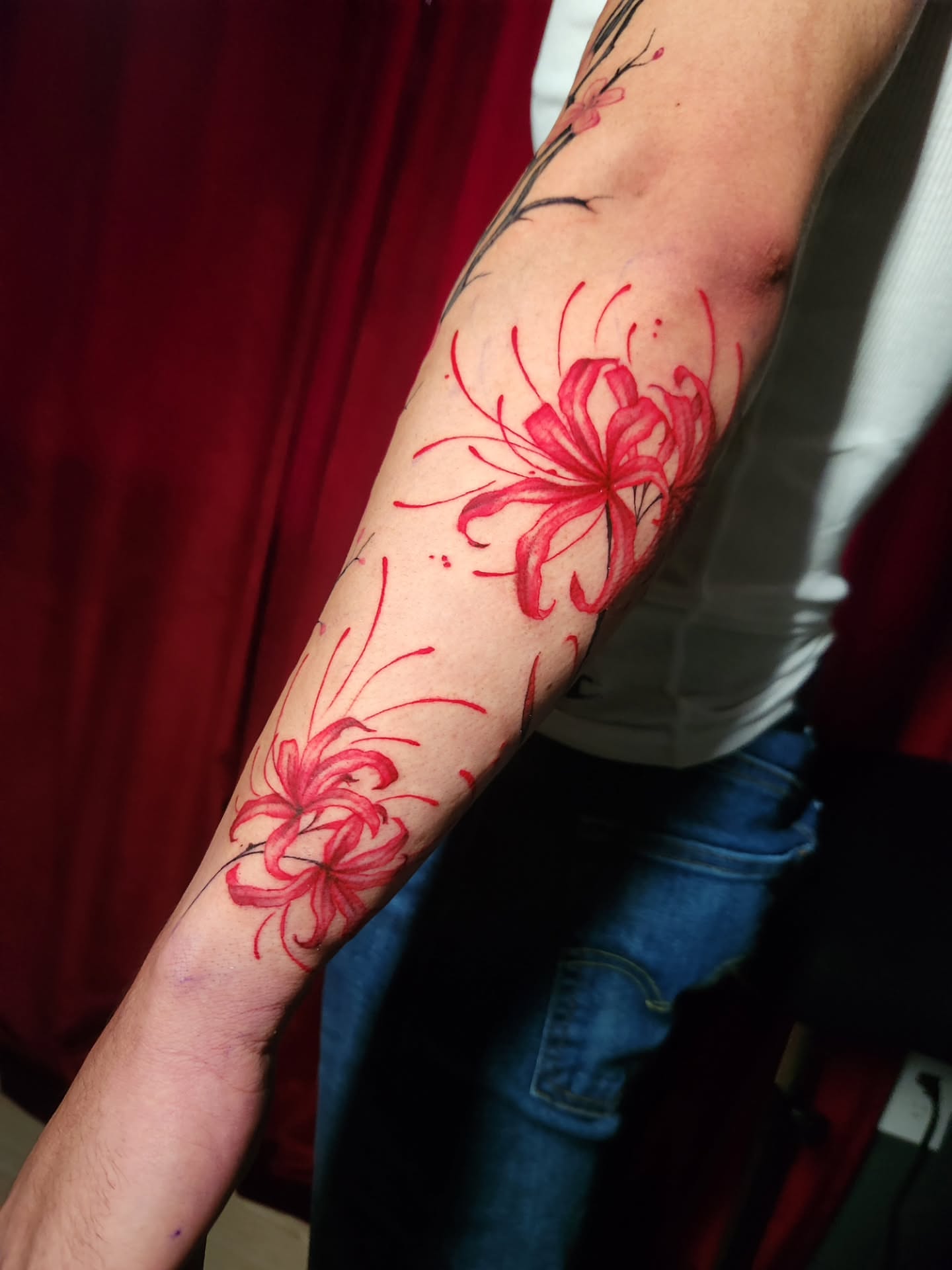 Red lilies watercolor tattoo on the forearm by Abby Renteria