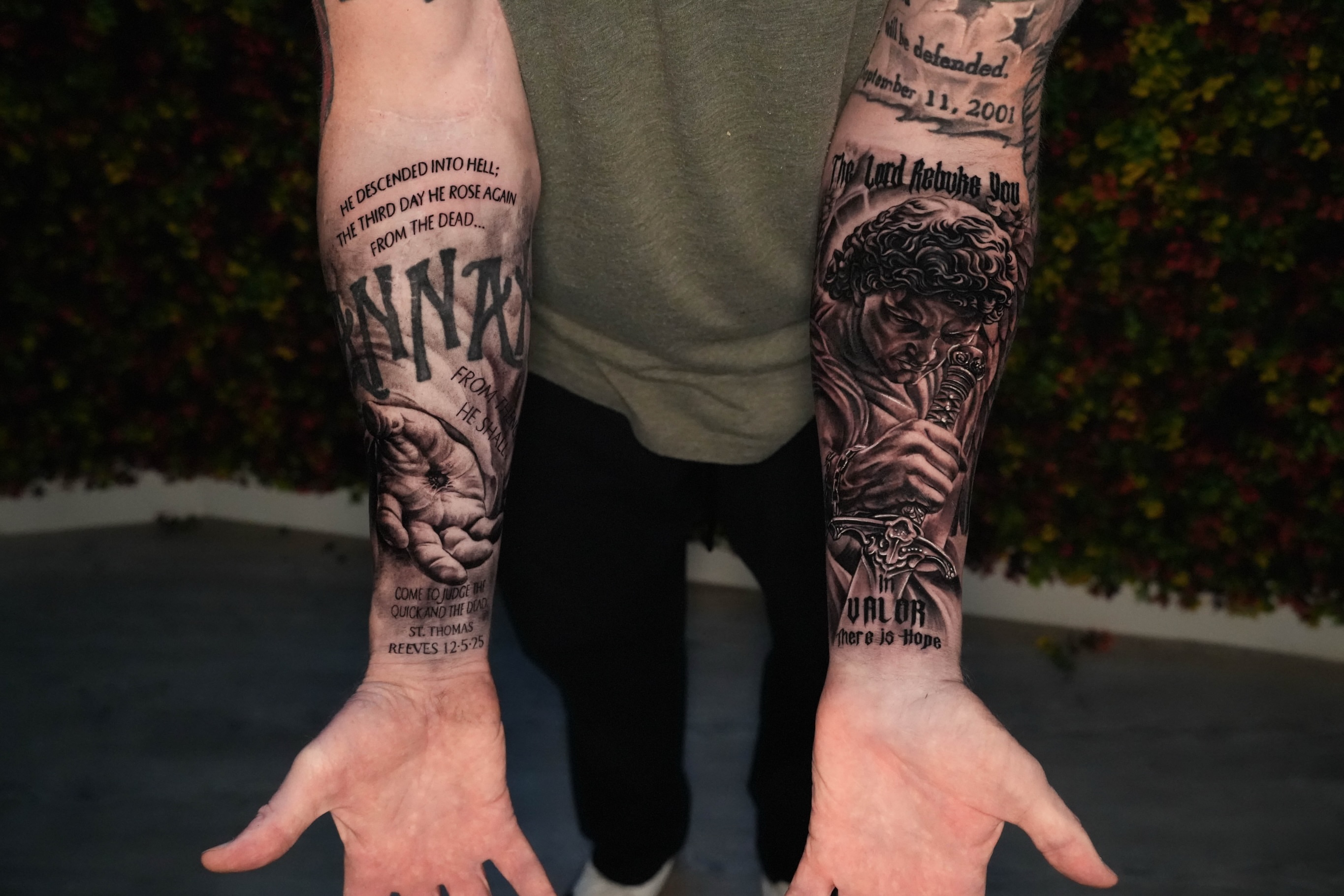 Religious text and figure black and grey tattoo on the forearm by Yudel