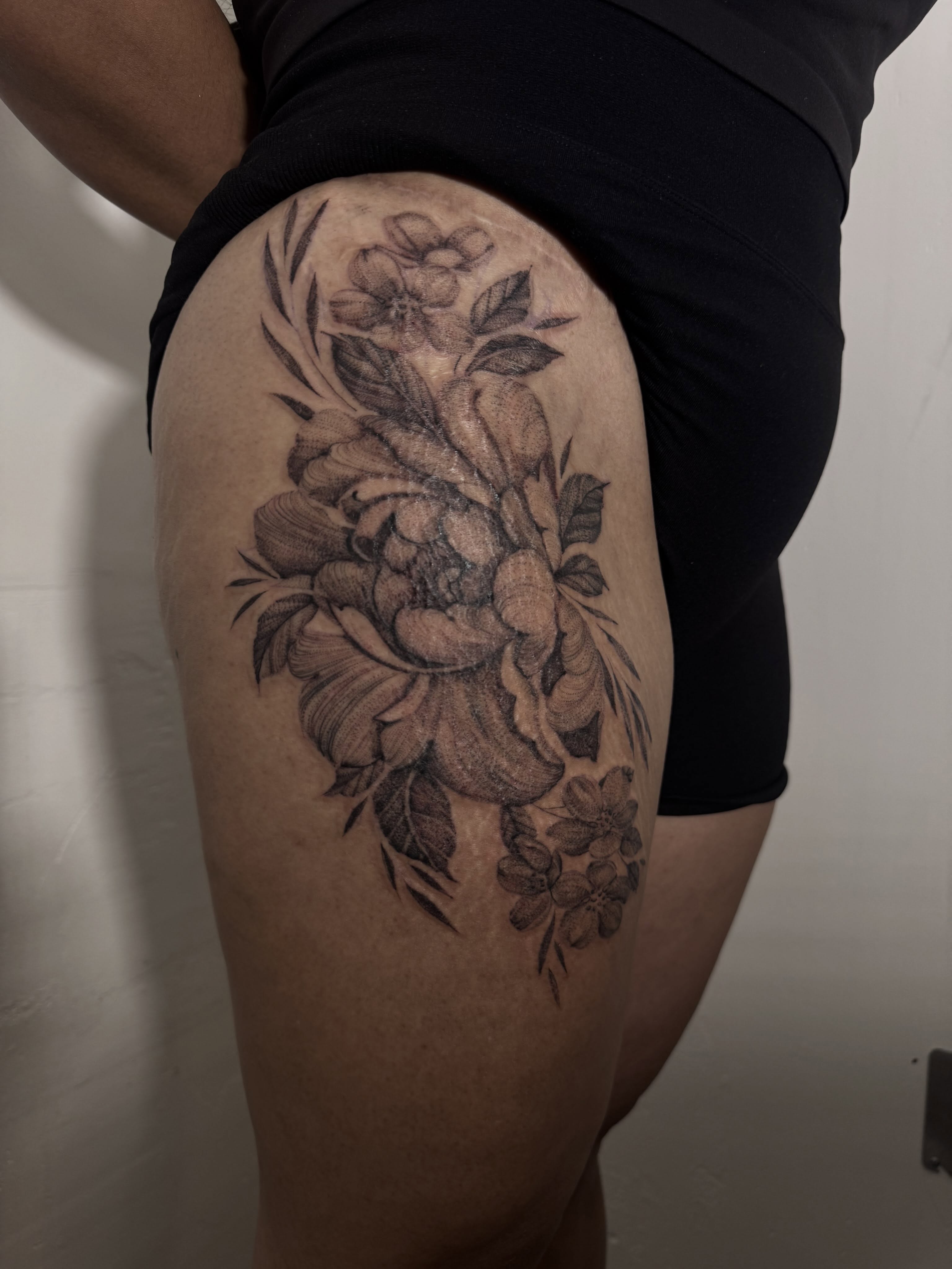 Floral bouquet realism tattoo on the thigh by Tianna Osborne