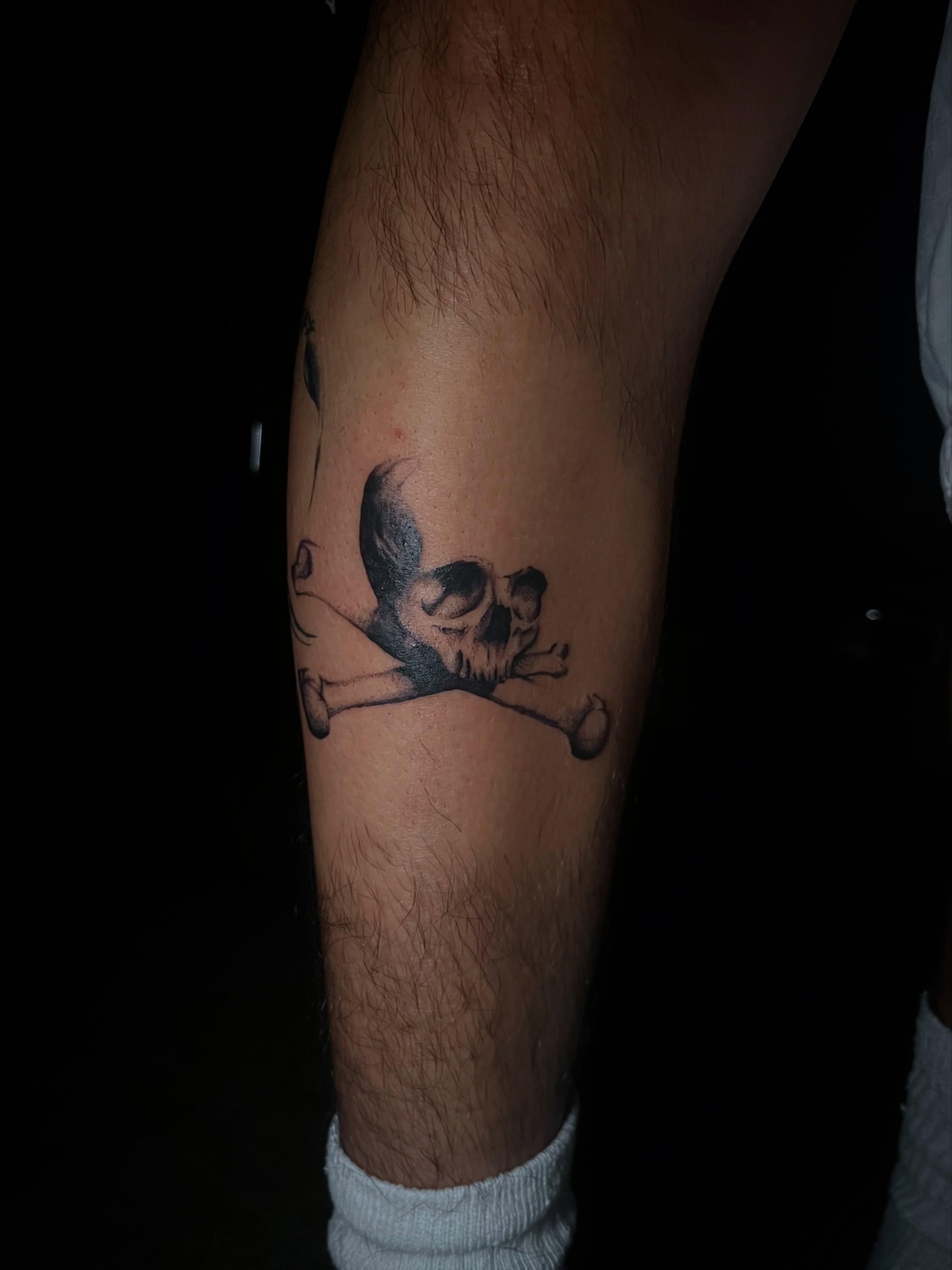 Skull and crossbones black and grey tattoo on the forearm by @halfwit__