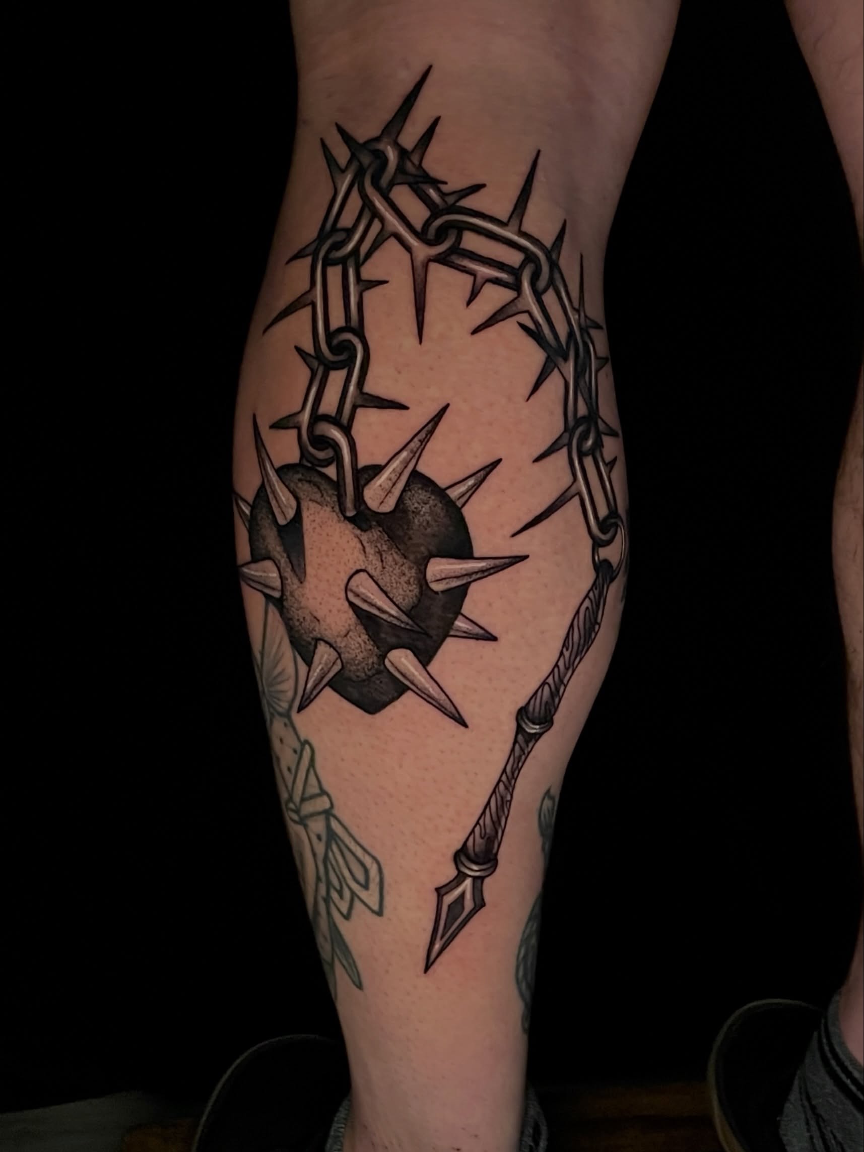 Barbed heart with chain black and grey tattoo on the calf by Austin Clark